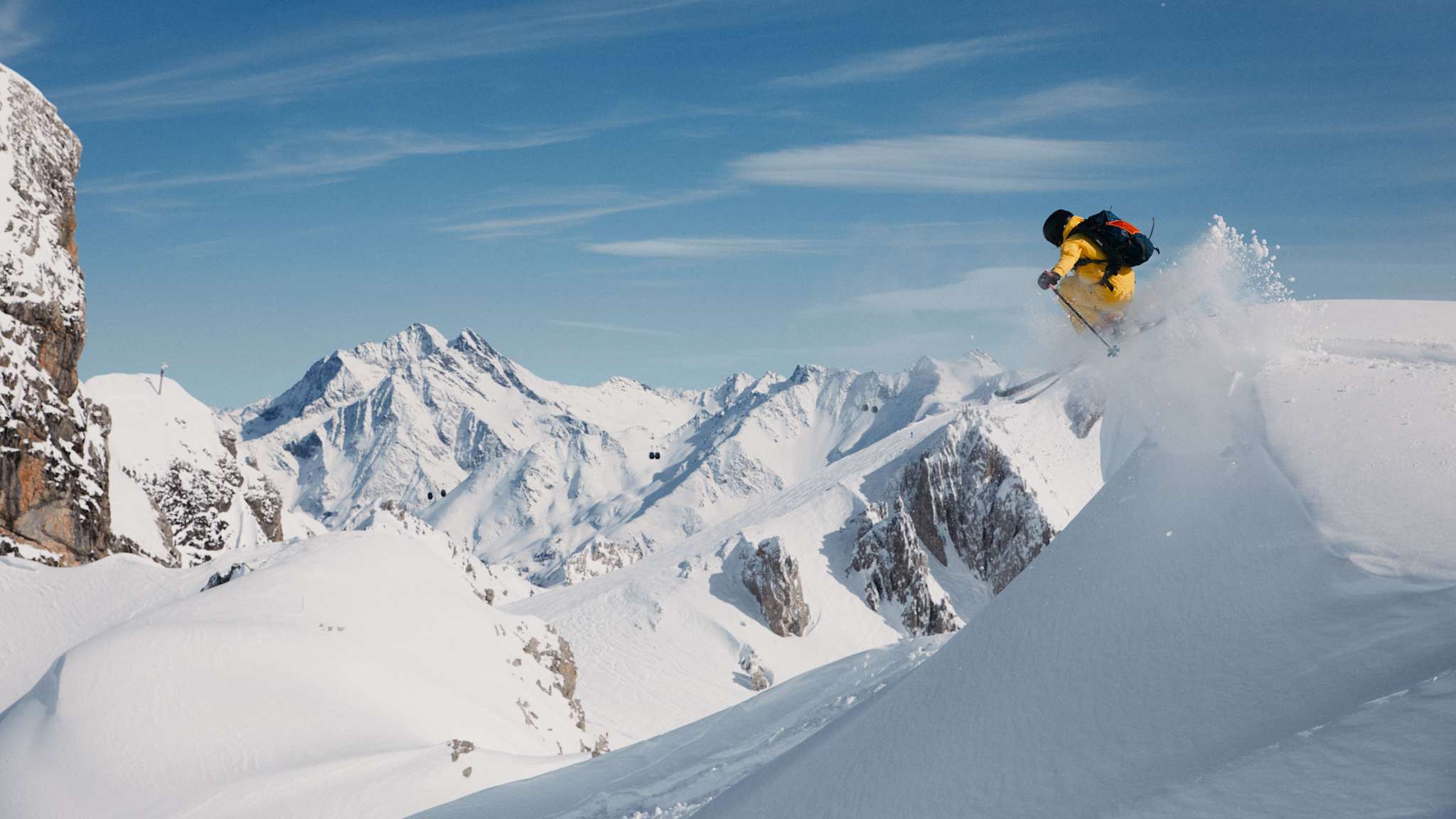Eine Person springt mit Skiern am Berg.
