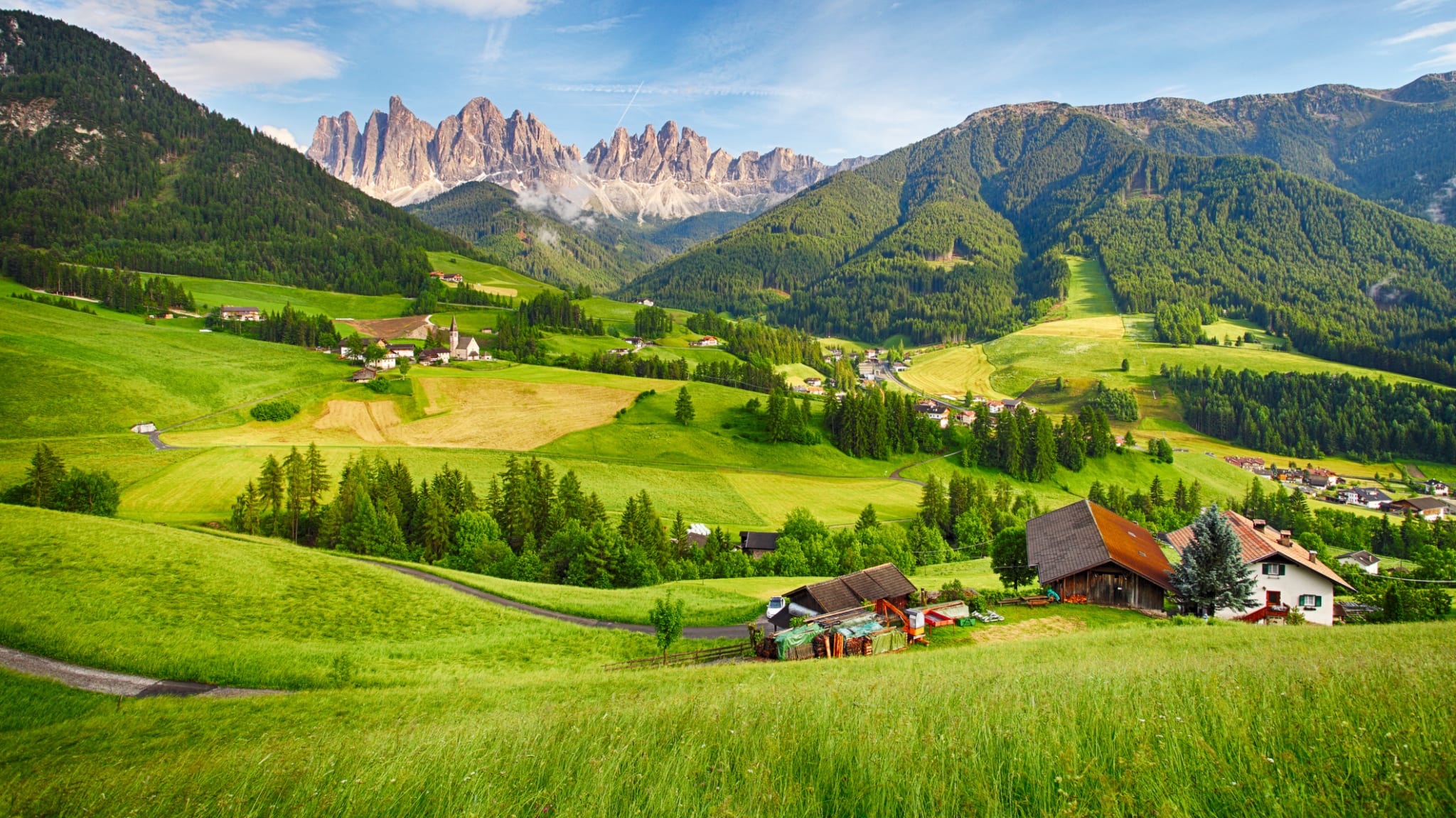 Schönes Bergpanorama mit den Dolomiten im Hintergrund und Hütten in grünem Tal © iStock.com/TomasSereda