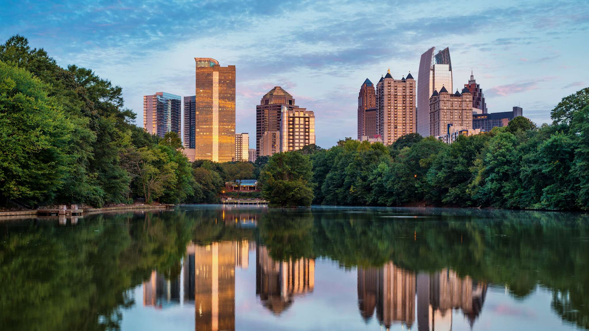 See in einem Park, im Hintergrund mehrere Hochhäuser, die sich im Wasser spiegeln