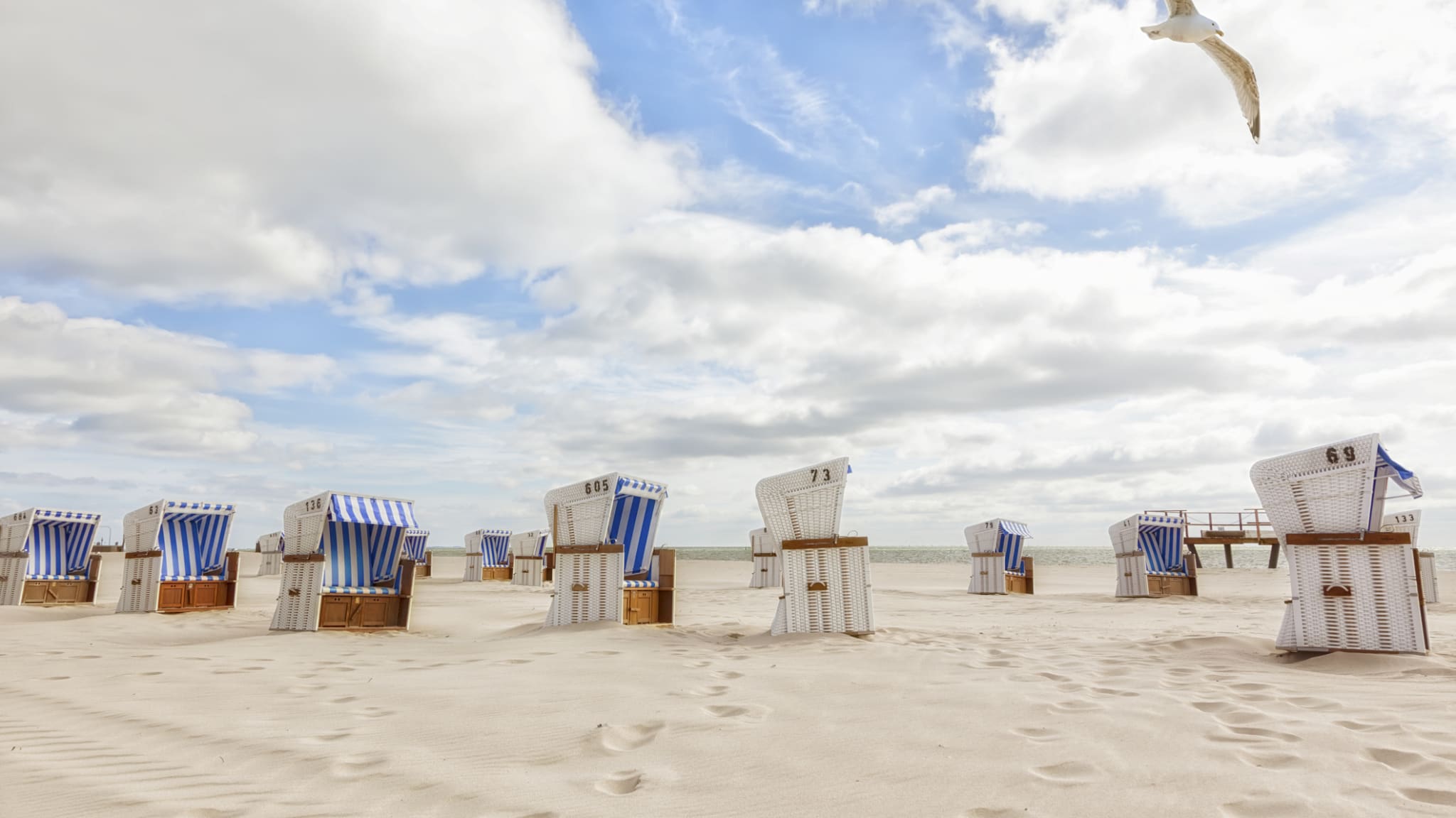Strand mit blau weiß gestreiften Strandkörben auf Sylt © iStock.com/eyewave