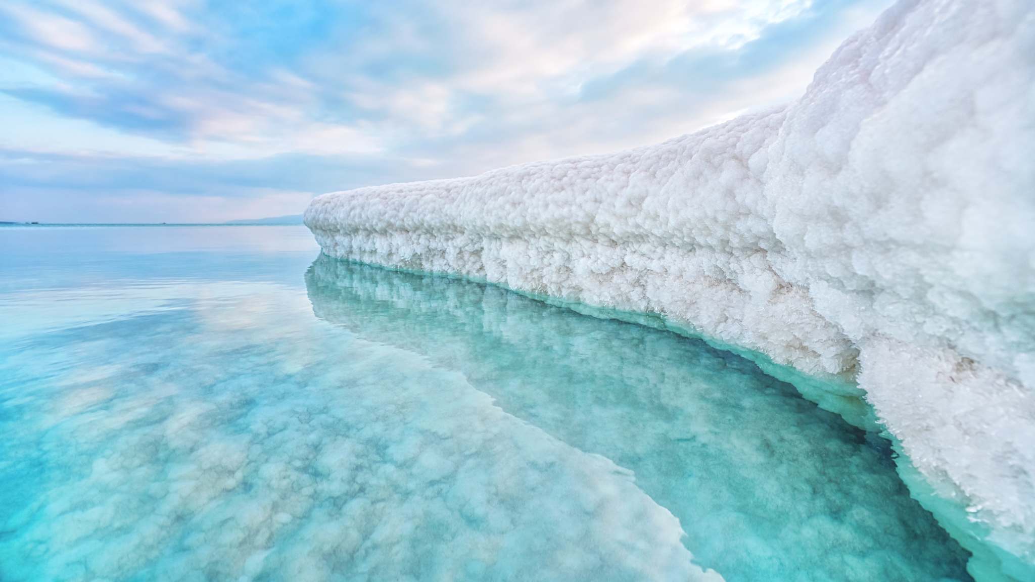 Sandbank bedeckt mit kristallinem Salz vom Toten Meer im hellblauen Meer vor ʿEin Bokek in Israel.