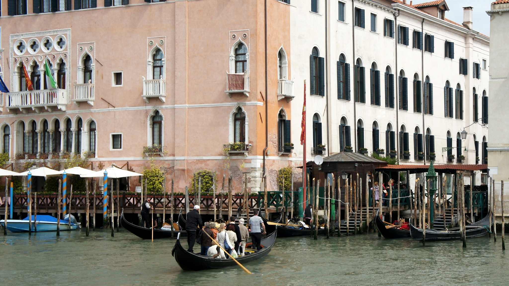 Ein schwarzes Traghetto fährt über den Canal Grande auf eine Häuserfront am anderen Ufer zu.