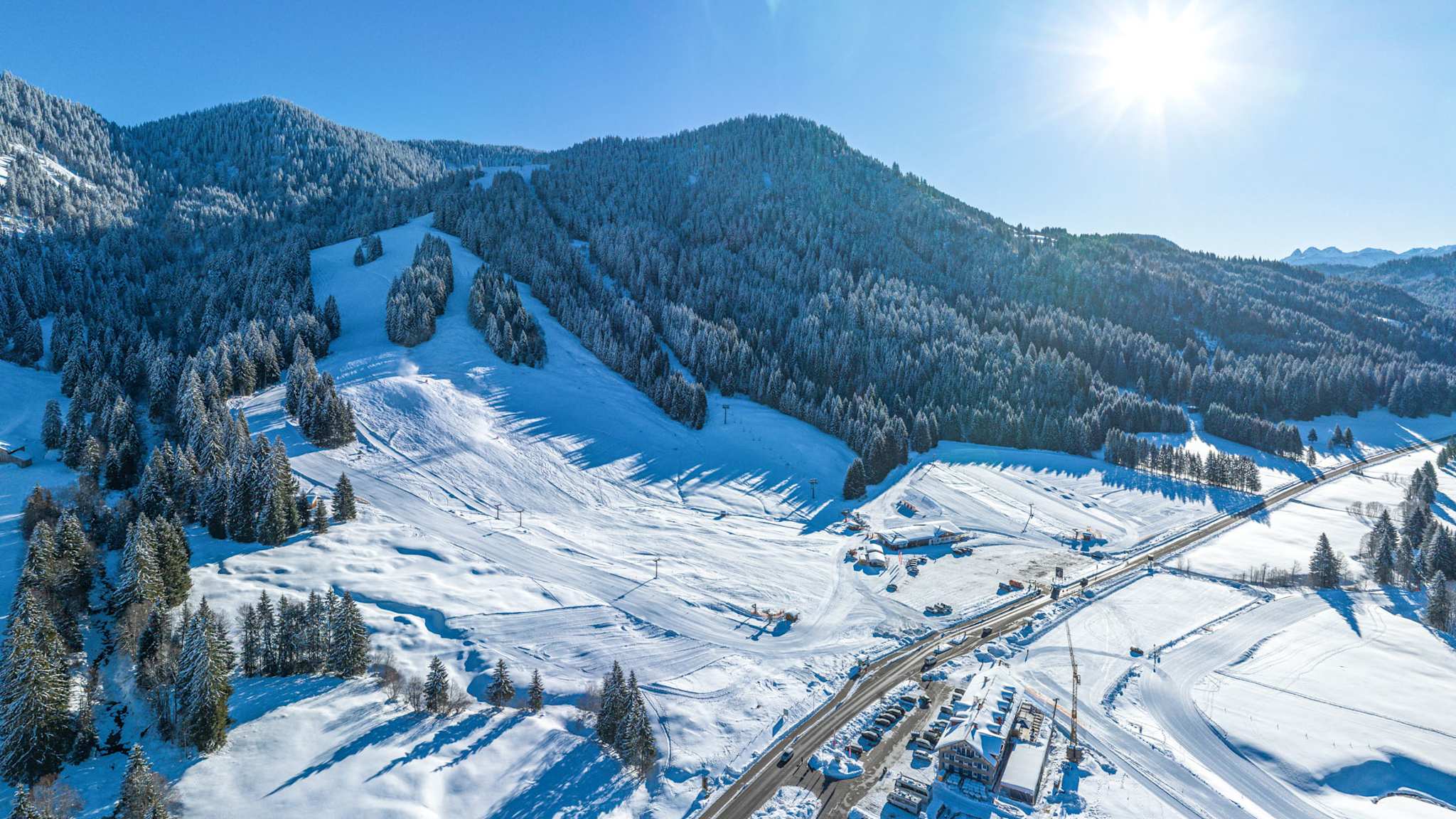 Winterliche Berglandschaft in Balderschwang mit Skipisten, Waldhängen und sonnigem Himmel