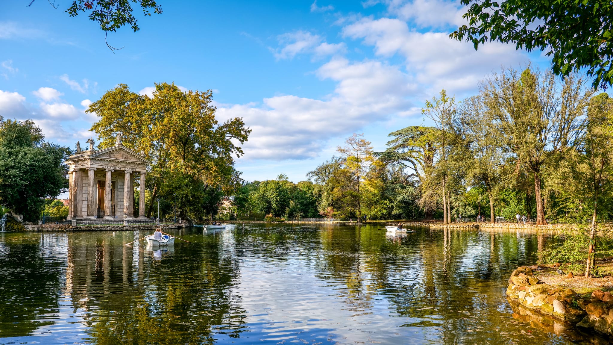 Boote auf einem Teich mit antiken Gebäuden im Hintergrund