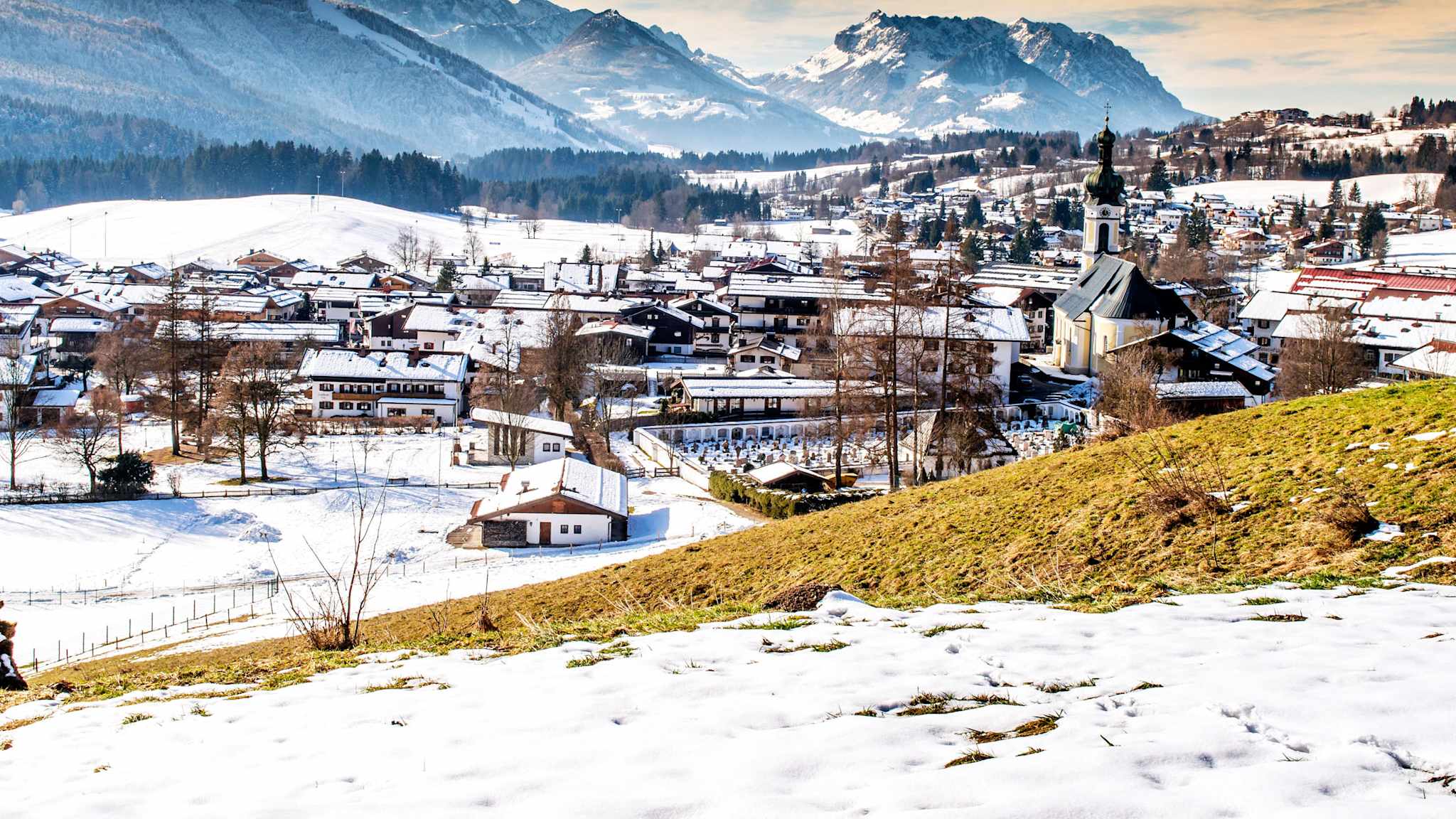 Panorama von Reit im Winkl im Winter, mit verschneitem Ortskern und Bergen im Hintergrund