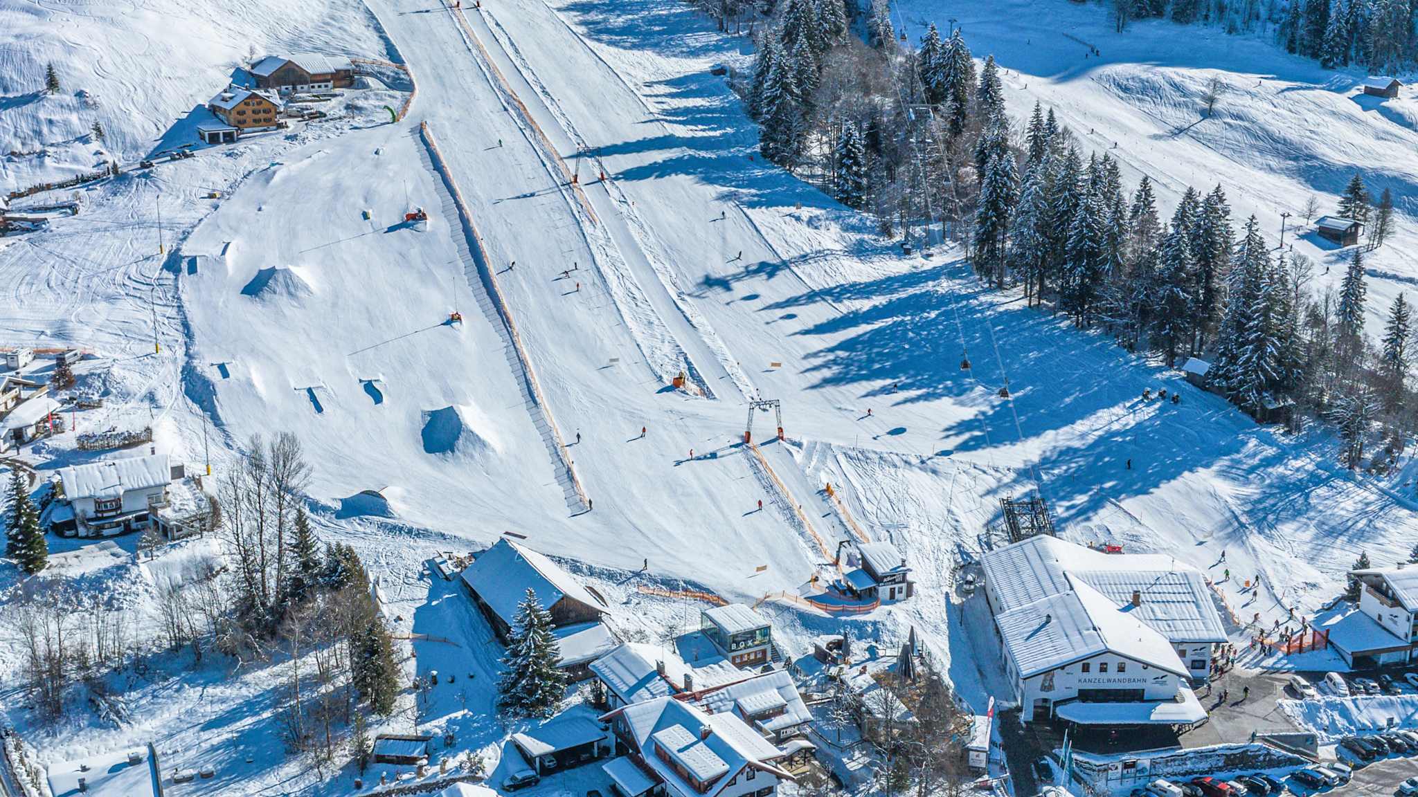 Blick von oben auf eine Schneelandschaft mit Piste und Häusern