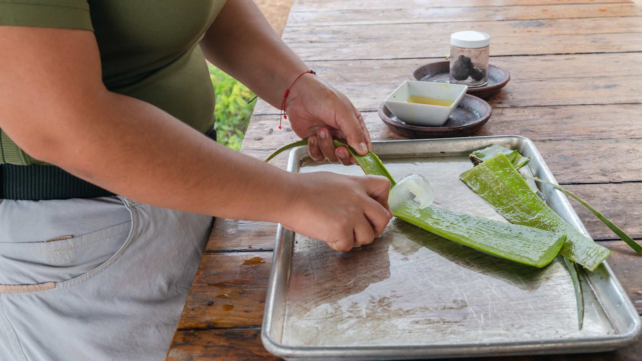 Eine Frau schabt eine Aloe Vera Pflanze aus.