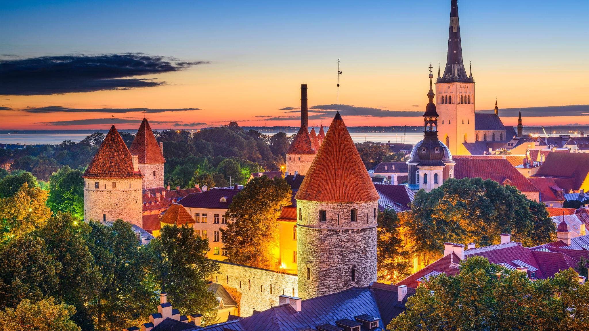 Man sieht über die Dächer einer Stadt mit zahlreichen mittelalterlichen Wehrtürmen und Kirchtürmen.