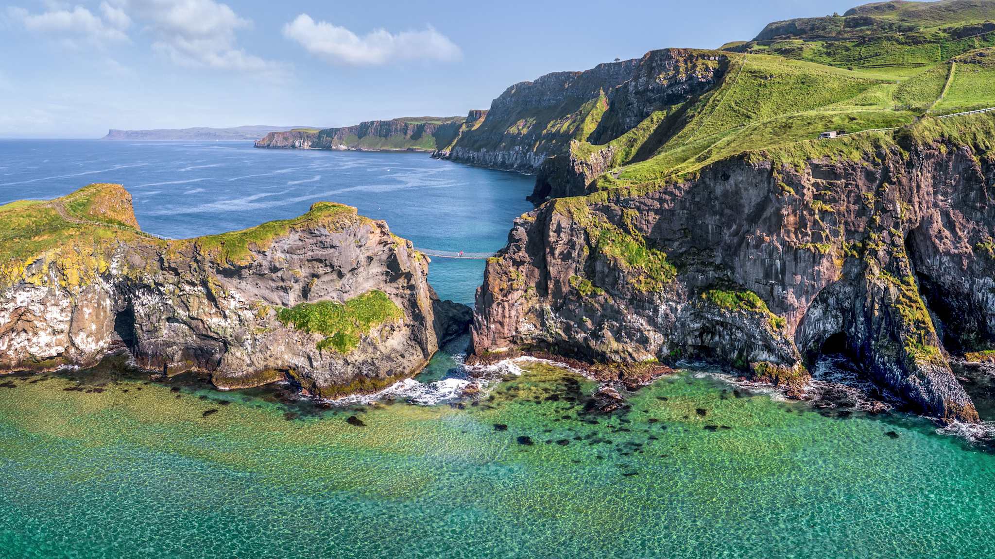 Eine Hängebrücke verbindet eine felsige Insel mit dem Festland.