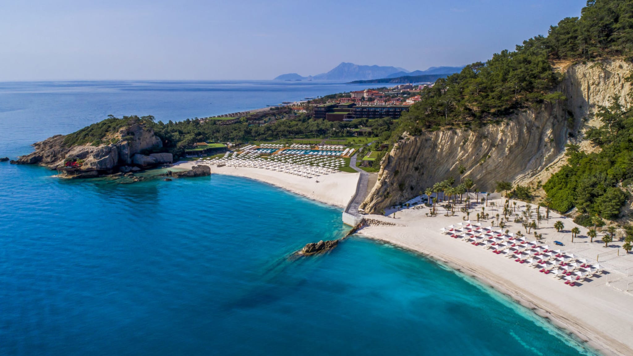 Strandabschnitt mit Felsen, Hotelgebäude und Meerblick im Maxx Royal Kemer Resort an der Türkischen Riviera
