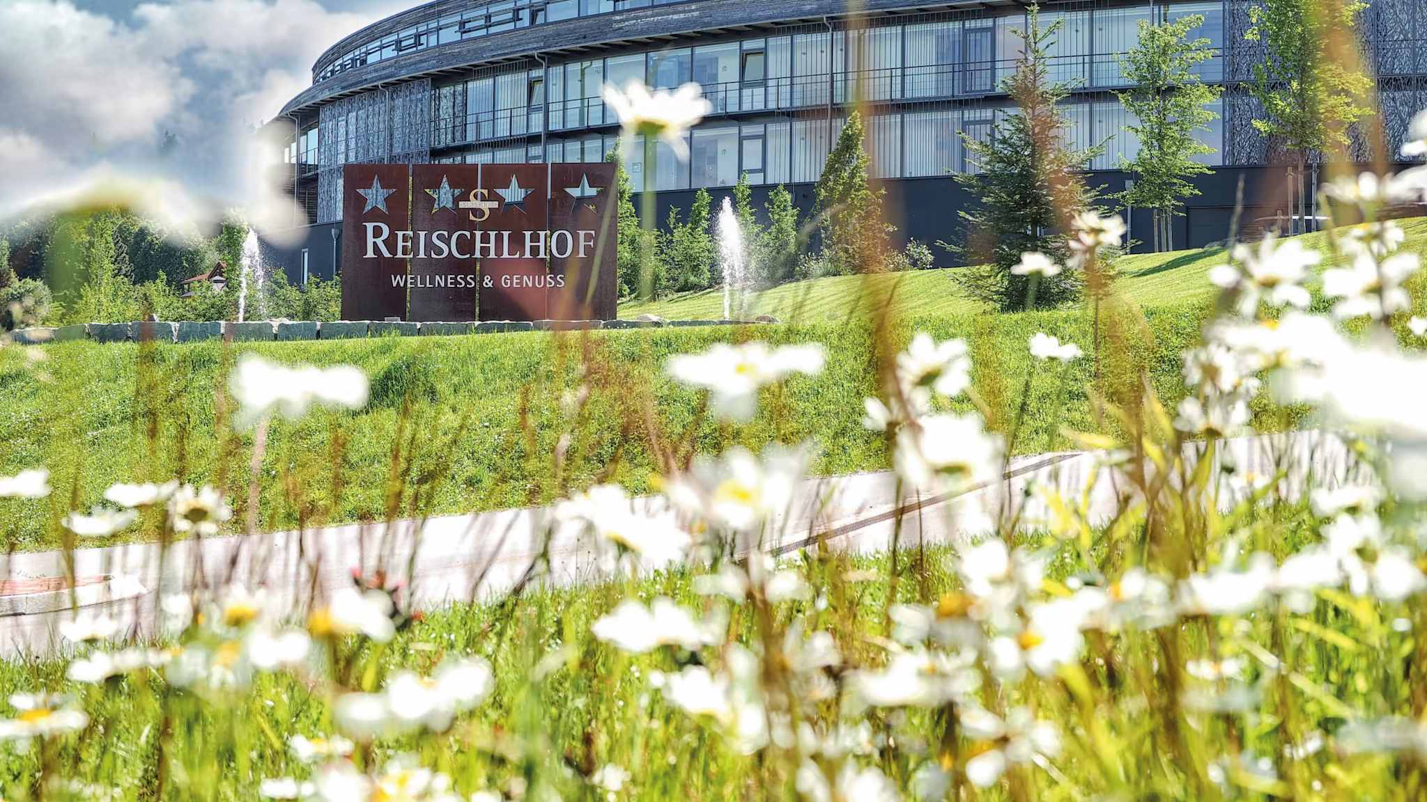 Außenanlage einer Hotelanlage, die von Wiesen umgeben ist