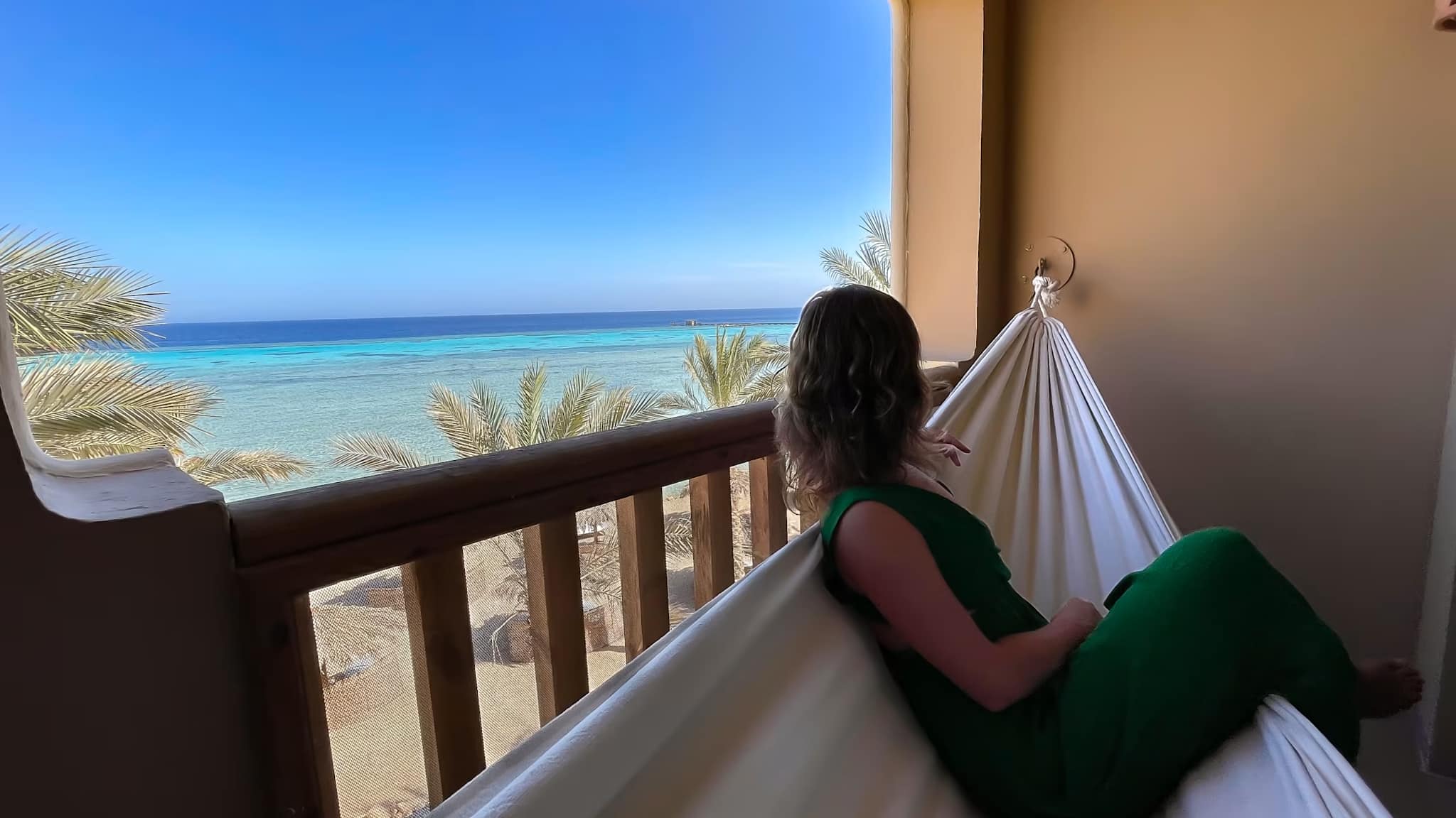 Eine Frau sitzt auf einer Hängematte auf dem Balkon ihres Hotelzimmers