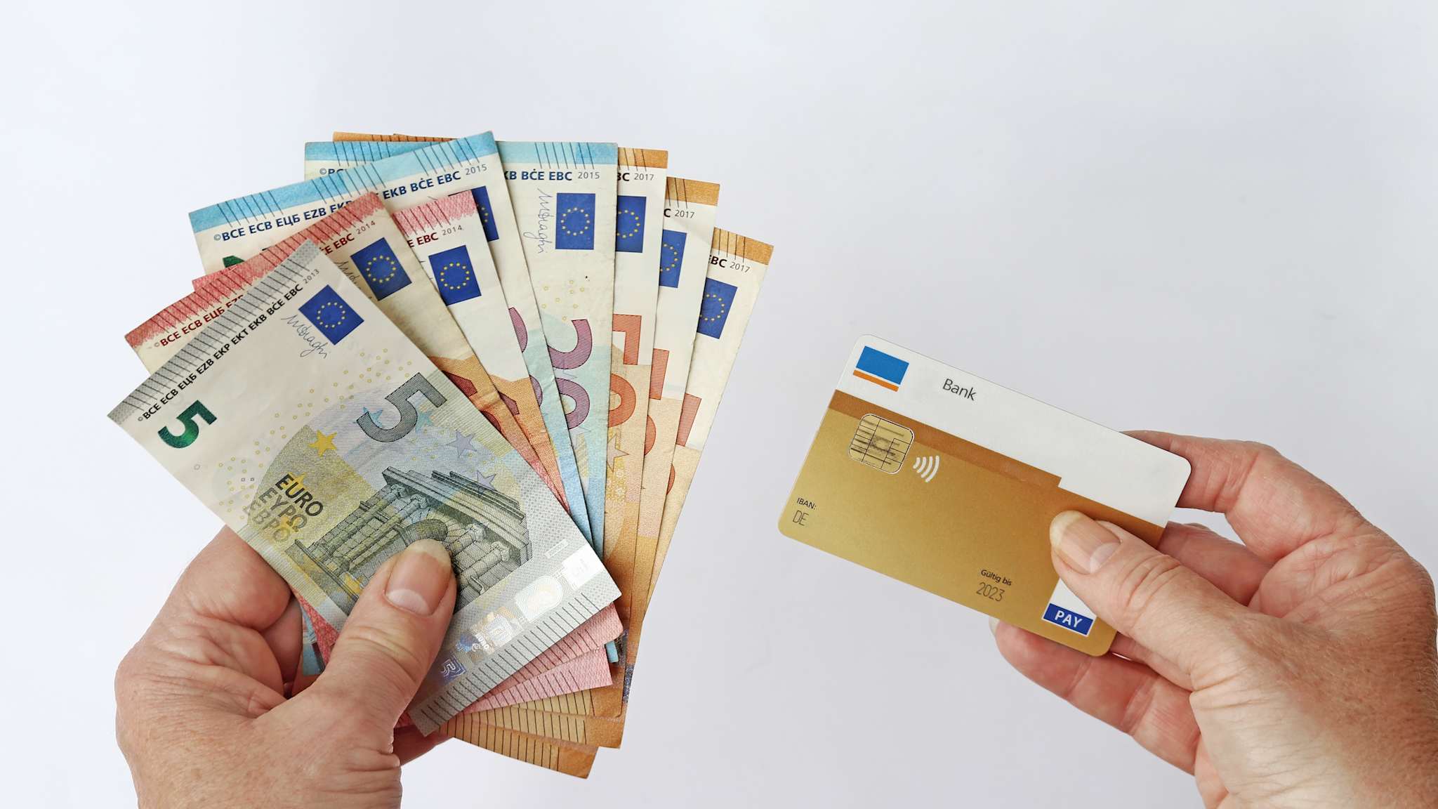 Eine Hand hält Euroscheine und die andere eine Bankkarte.