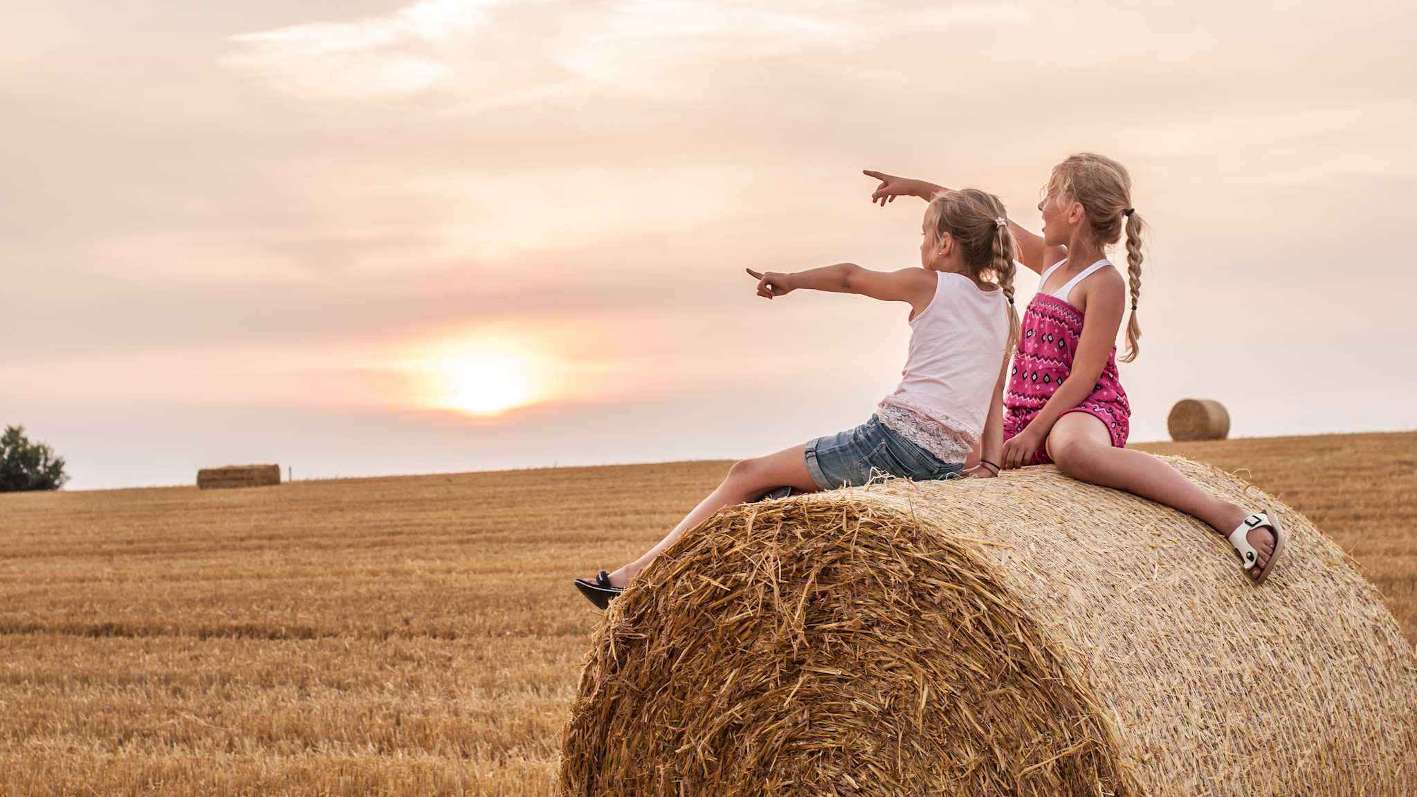 Zwei Mädchen sitzen auf einem Bauernhof.