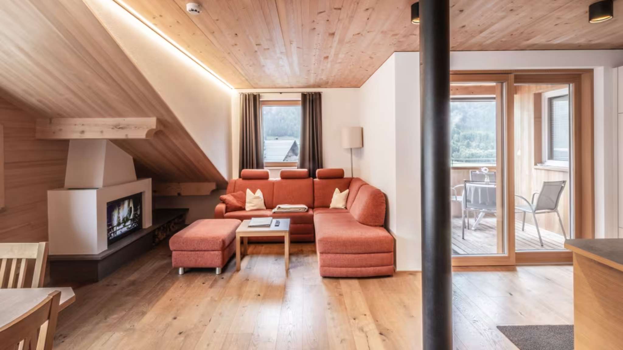 Blick auf einen offenen Raum mit Ecksofa und Feuerstelle.