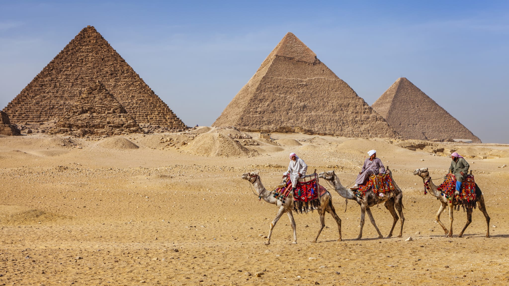 Beduinen auf Kamelen vor den Pyramiden von Gizeh, Ägypten