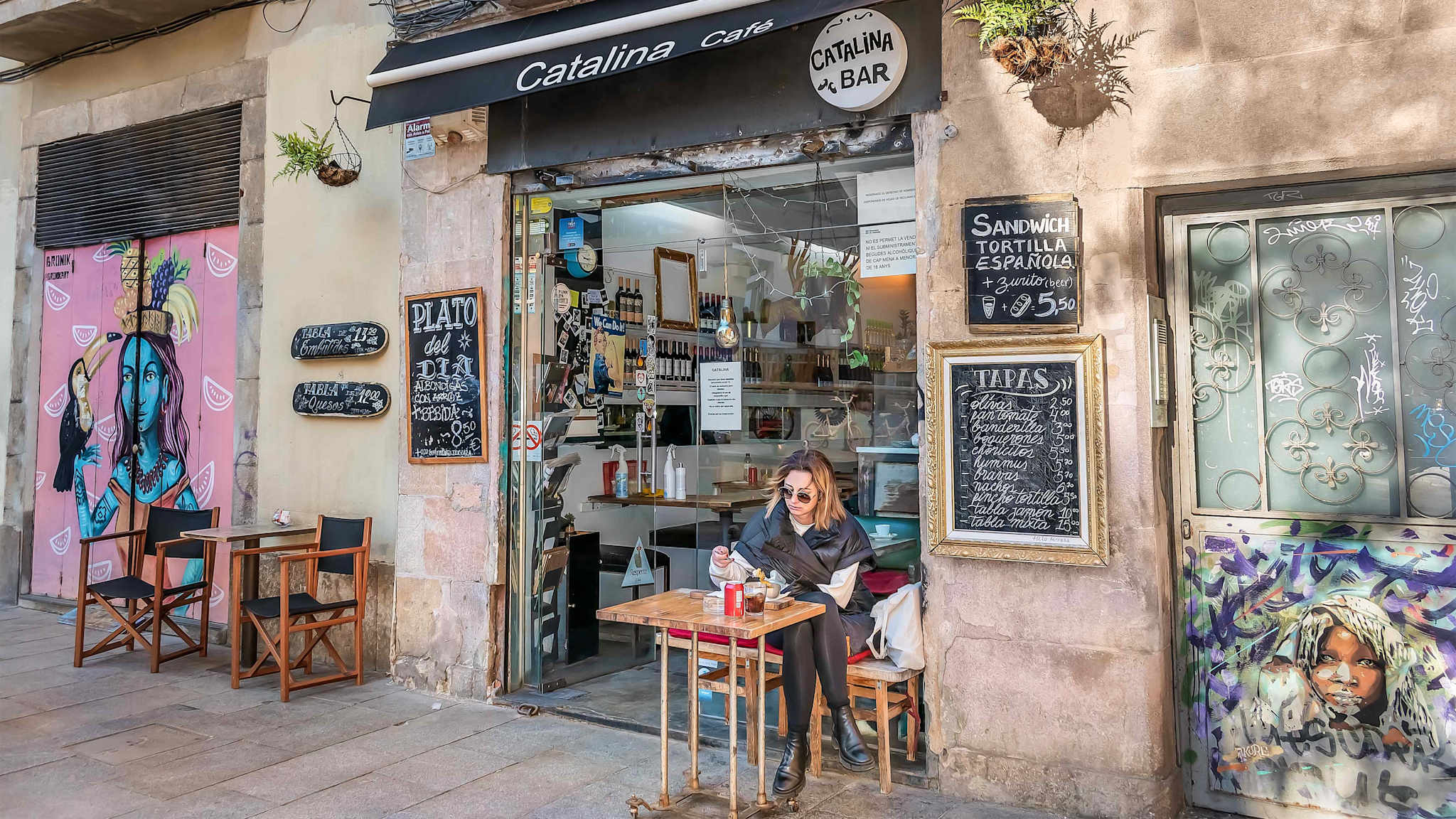 Eine Frau sitzt vor einem Café in Barcelona.