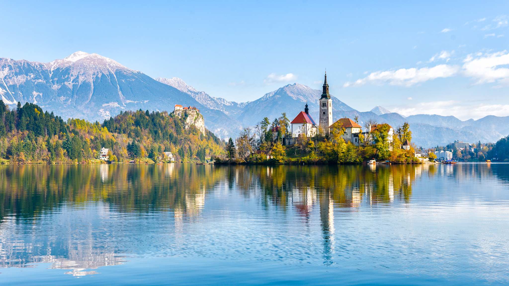 Eine Kirche auf einer Insel in einem See, vor einer Bergkulisse.