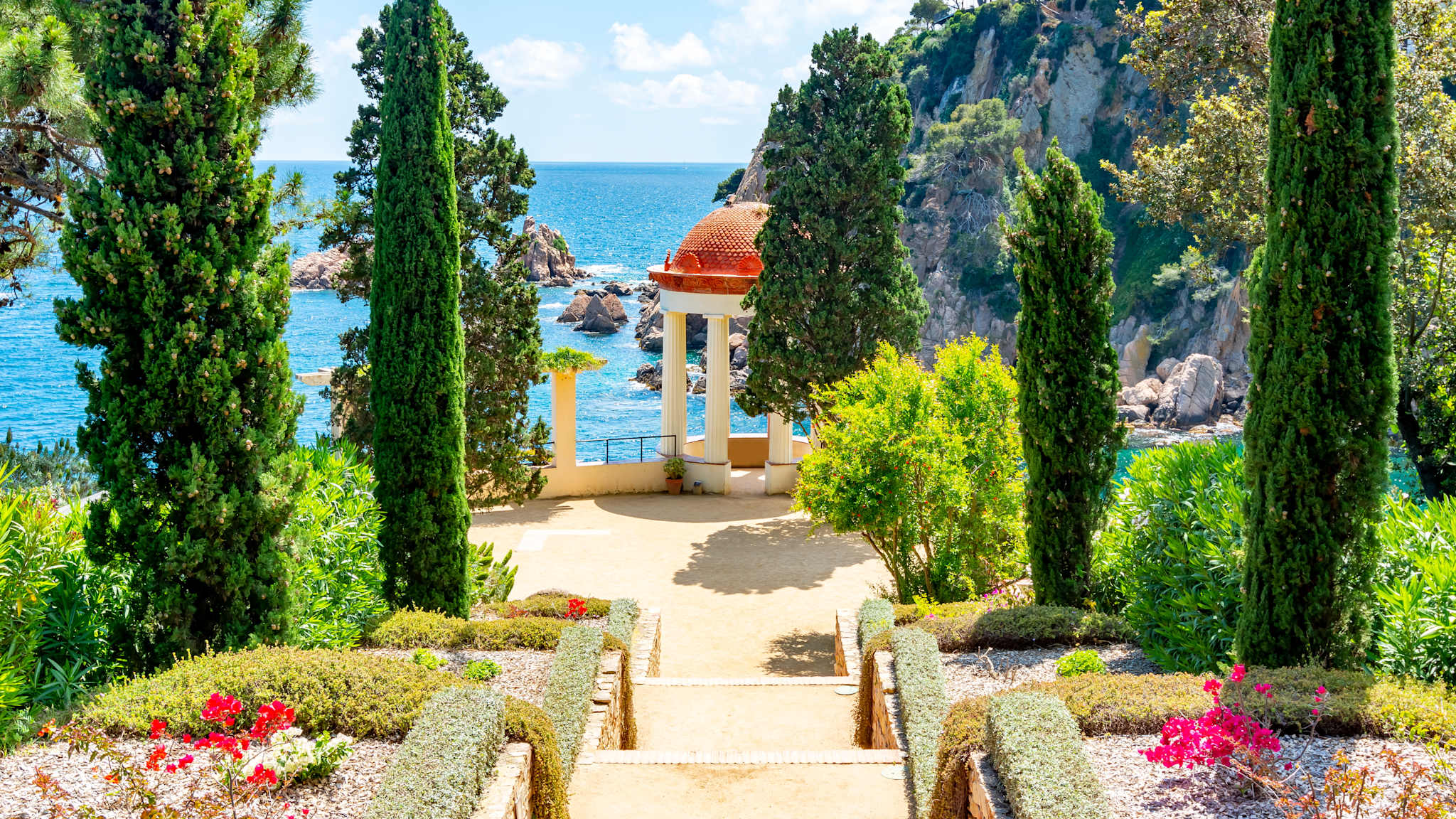 Ein kleiner Rundtempel steht auf einer Klippe über dem Meer.