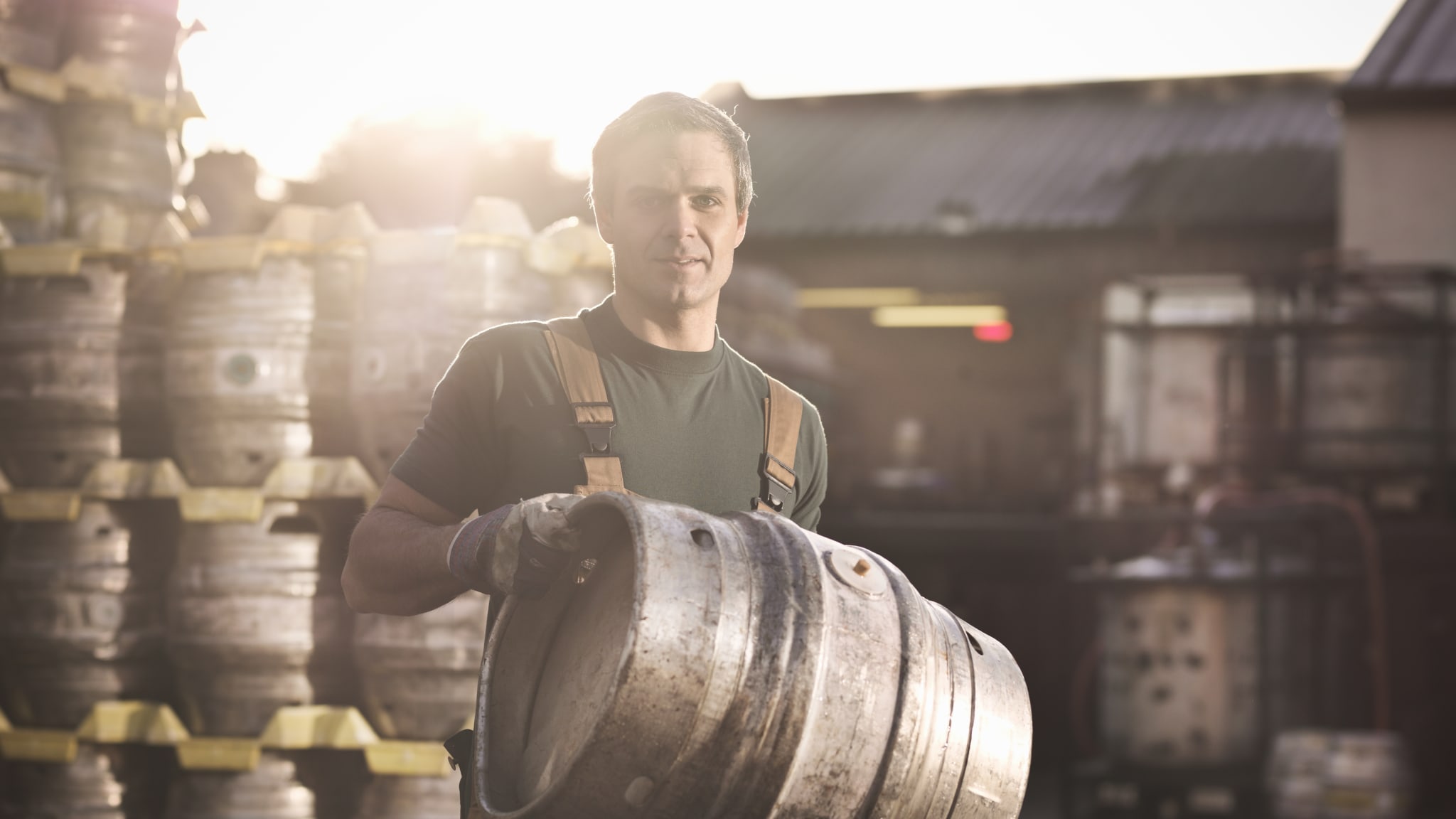 Mitarbeiter einer Brauerei trägt ein Bierfass © Monty Rakusen