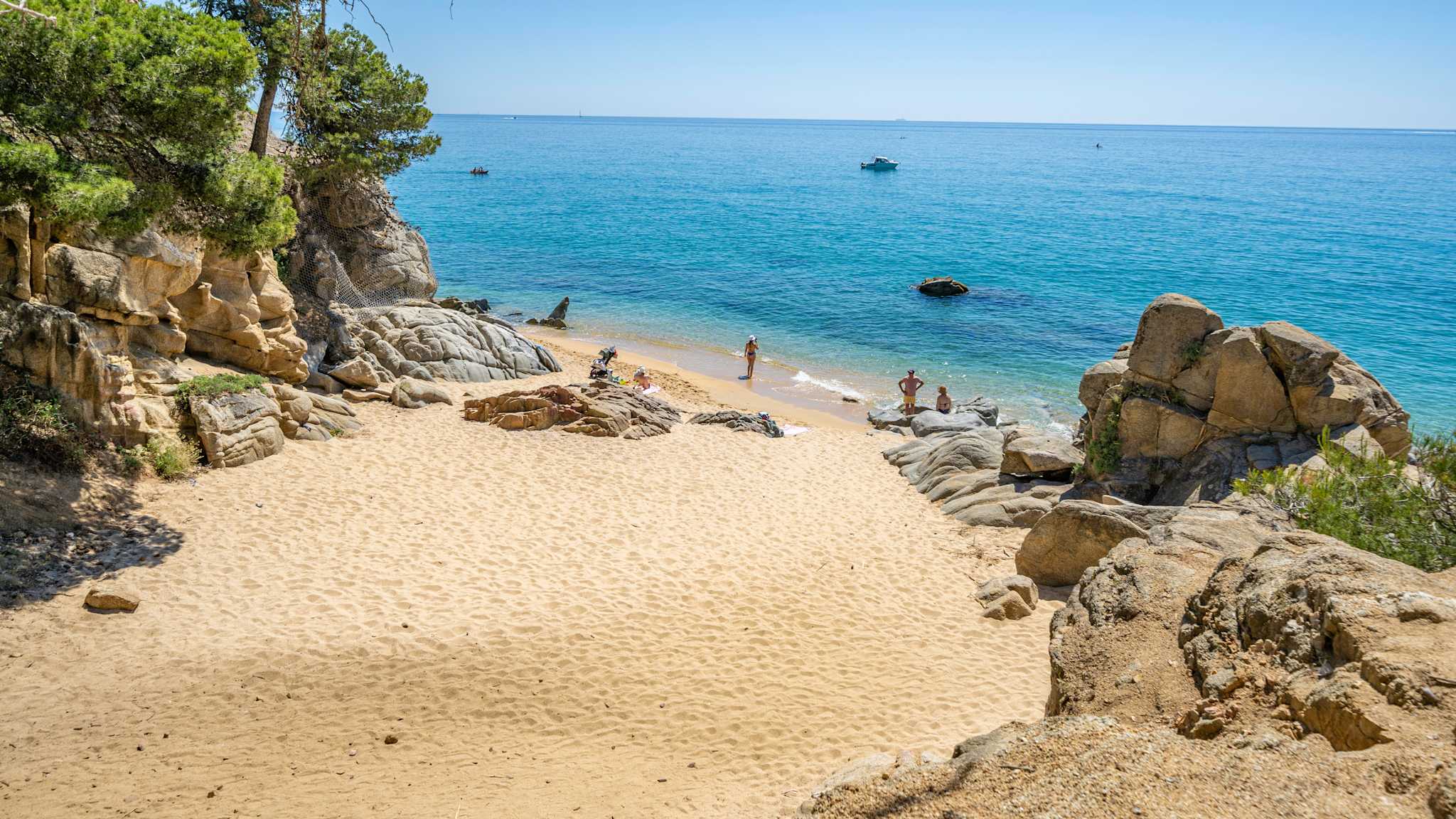 Menschen entspannen an einem Strand zwischen Felsen.