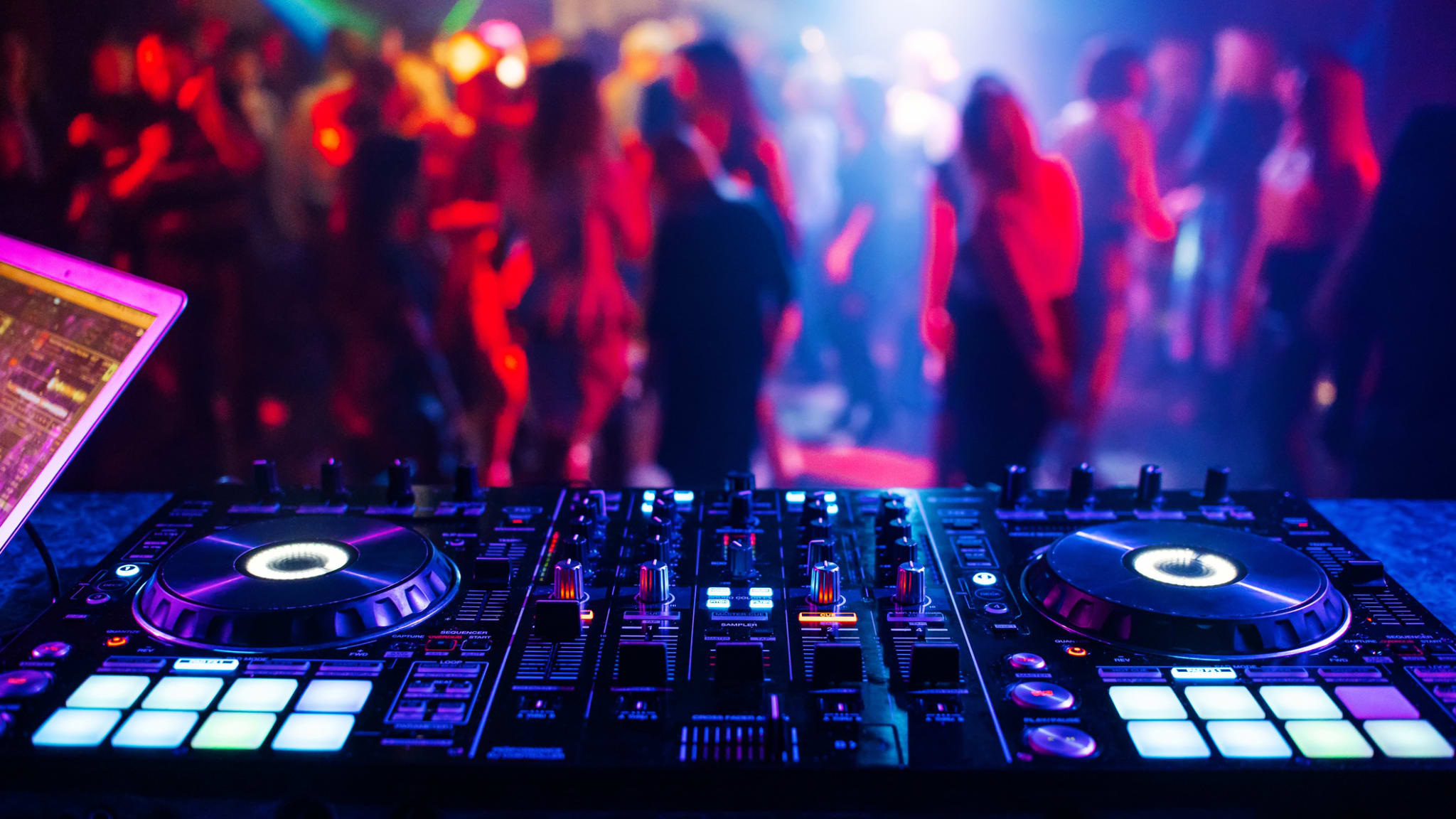 DJ-Mixer in einem Nachtclub vor einer tanzenden Menge. © alexkoral/iStock / Getty Images Plus via Getty Images