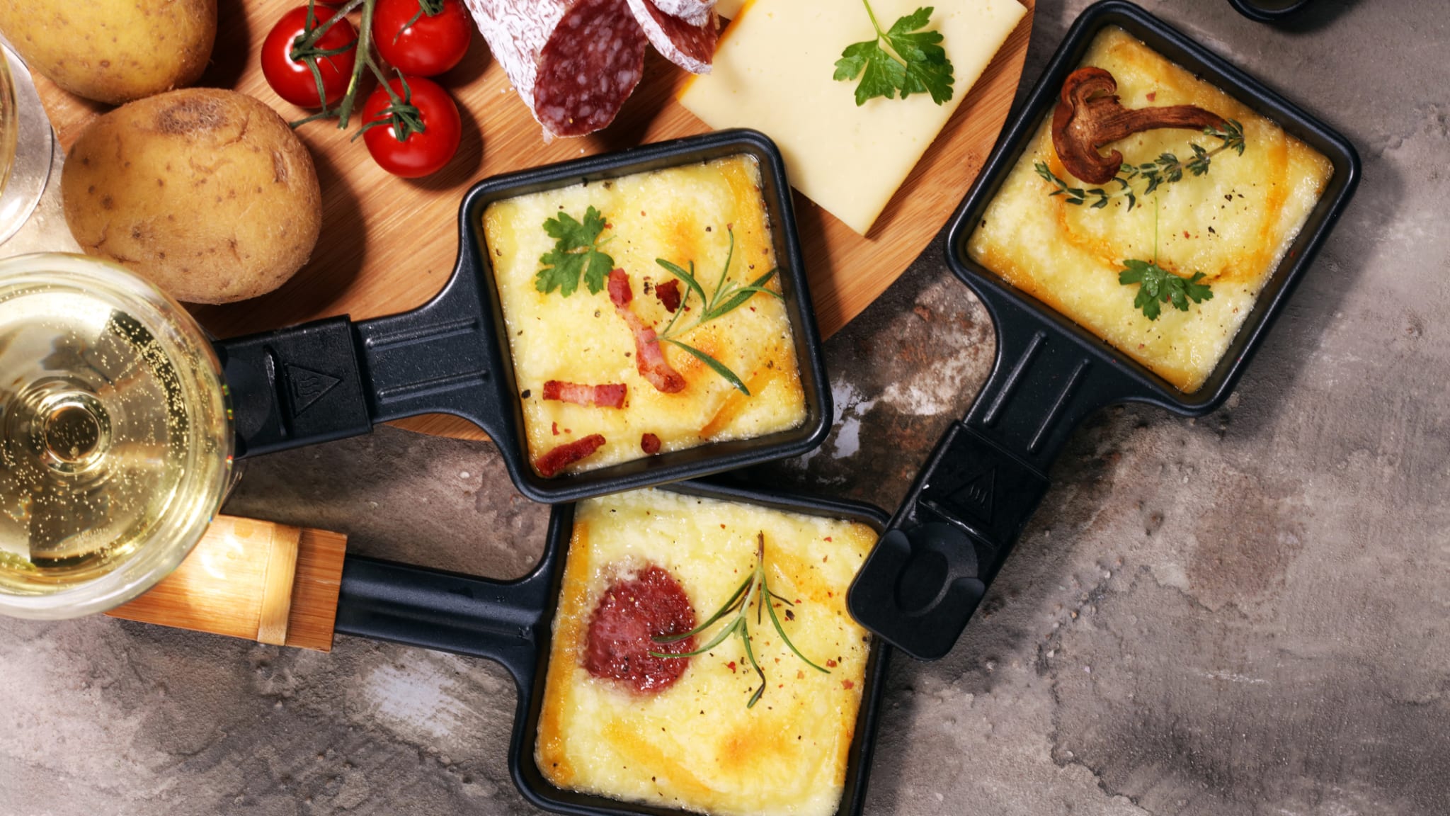 Drei kleine Pfännchen mit geschmolzenem Raclettekäse. © beats3/iStock / Getty Images Plus via Getty Images