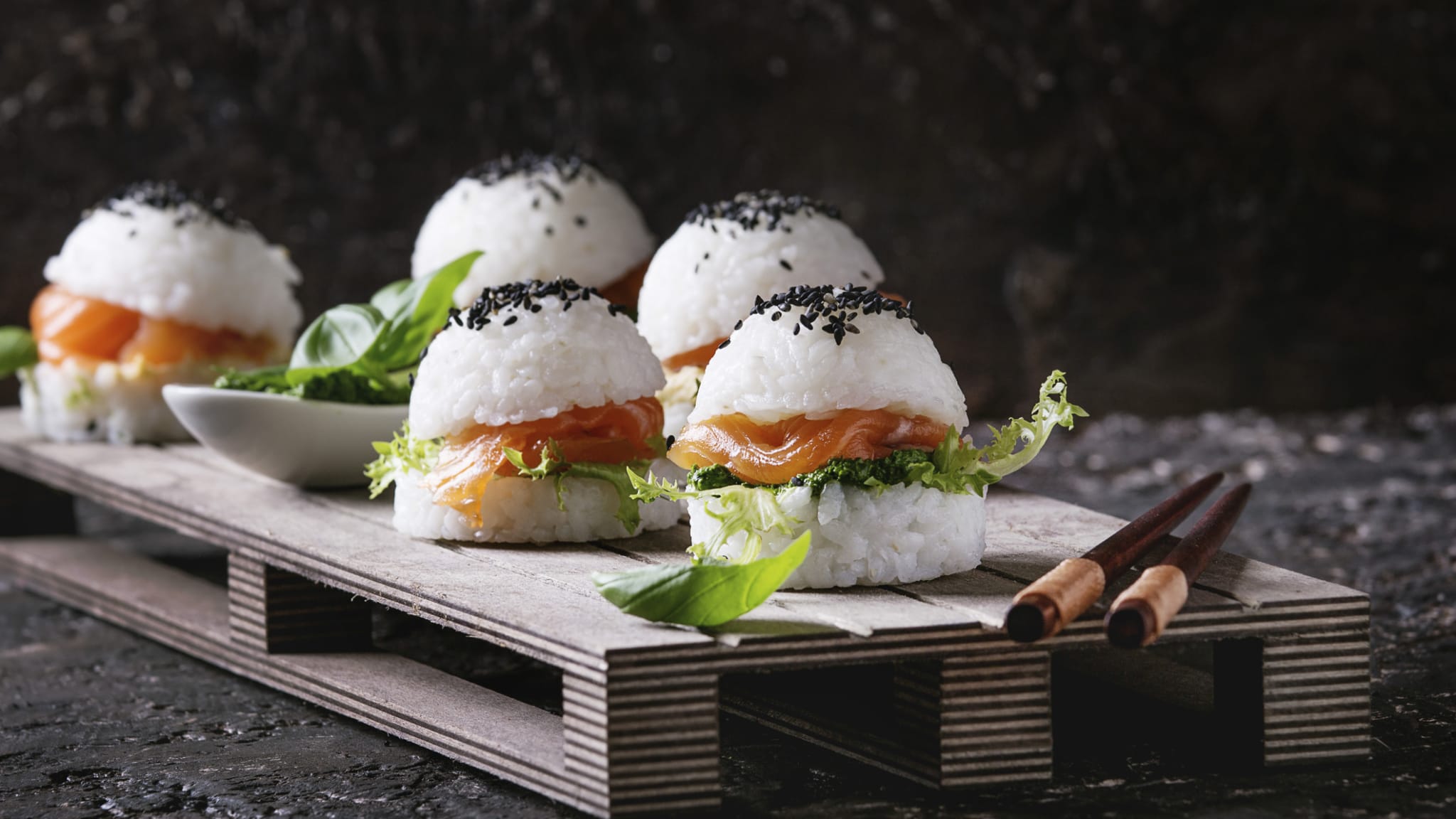 Ein Holzbrett mit mehreren Sushi-Burgern.