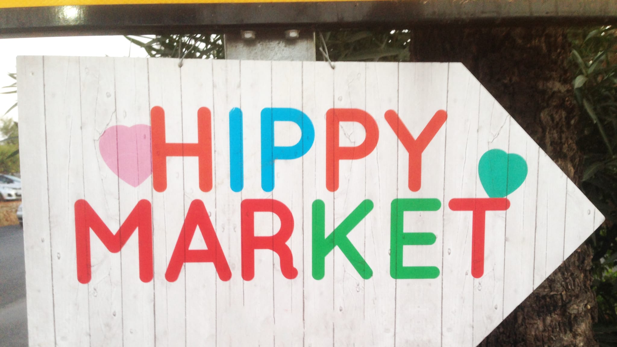 Ein Holzschild mit der Aufschrift “Hippy Market” in bunten Buchstaben.
