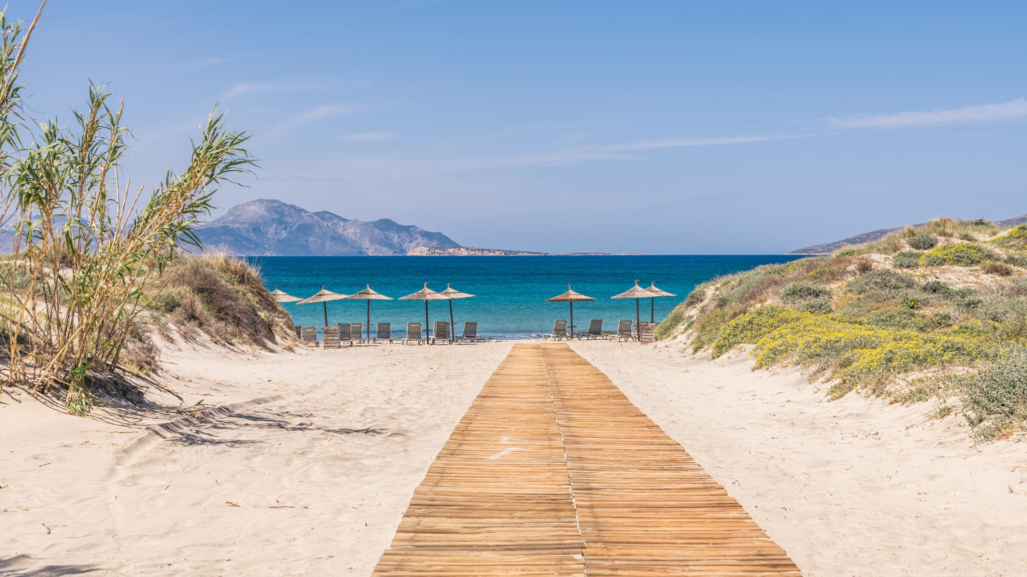 Ein Holzweg zu einem Strand auf Kos, Griechenland. © George Papapostolou photographer/Moment via Getty Images