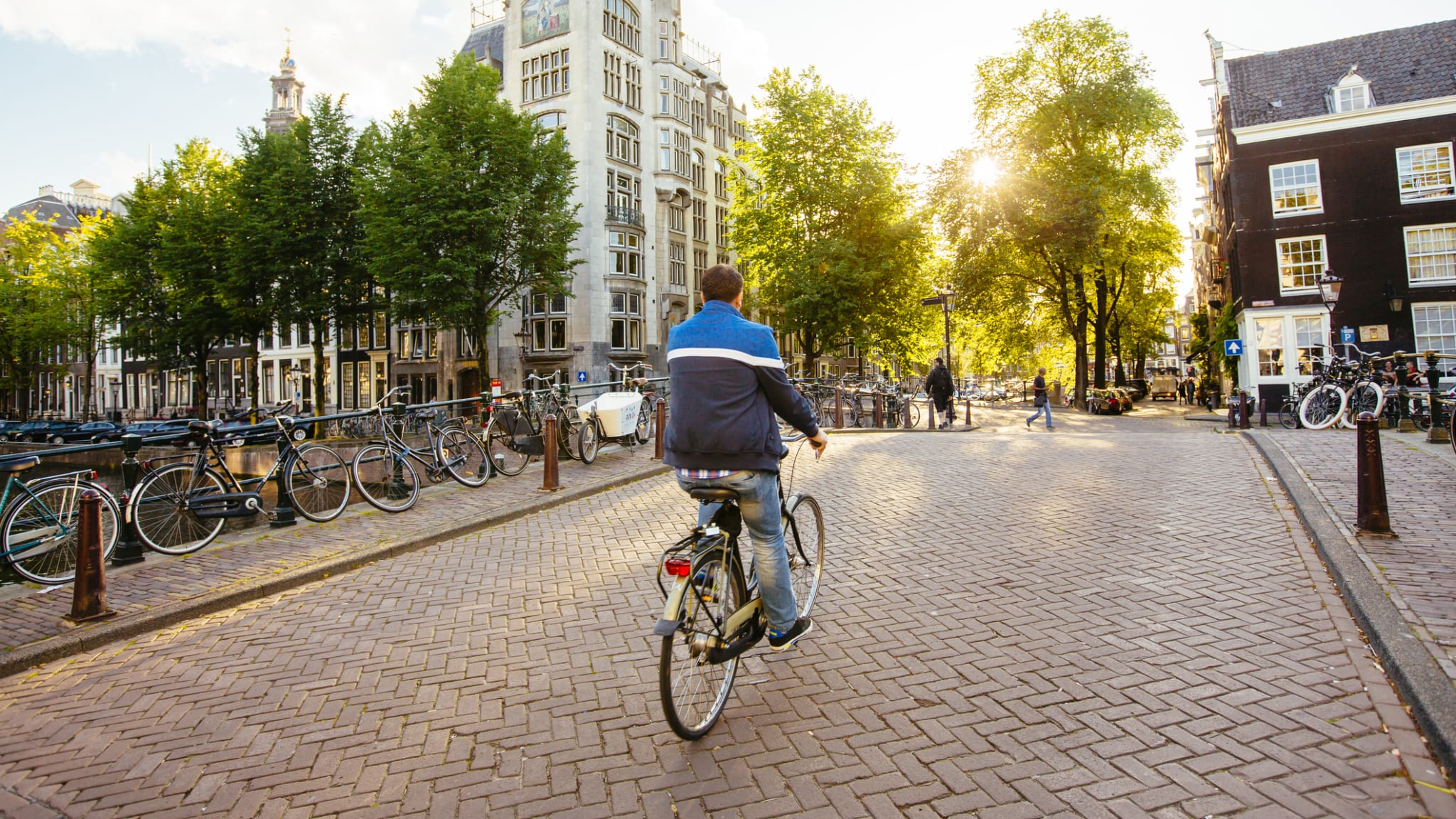 Ein Mann fährt mit dem Fahrrad über eine Brücke in Amsterdam.