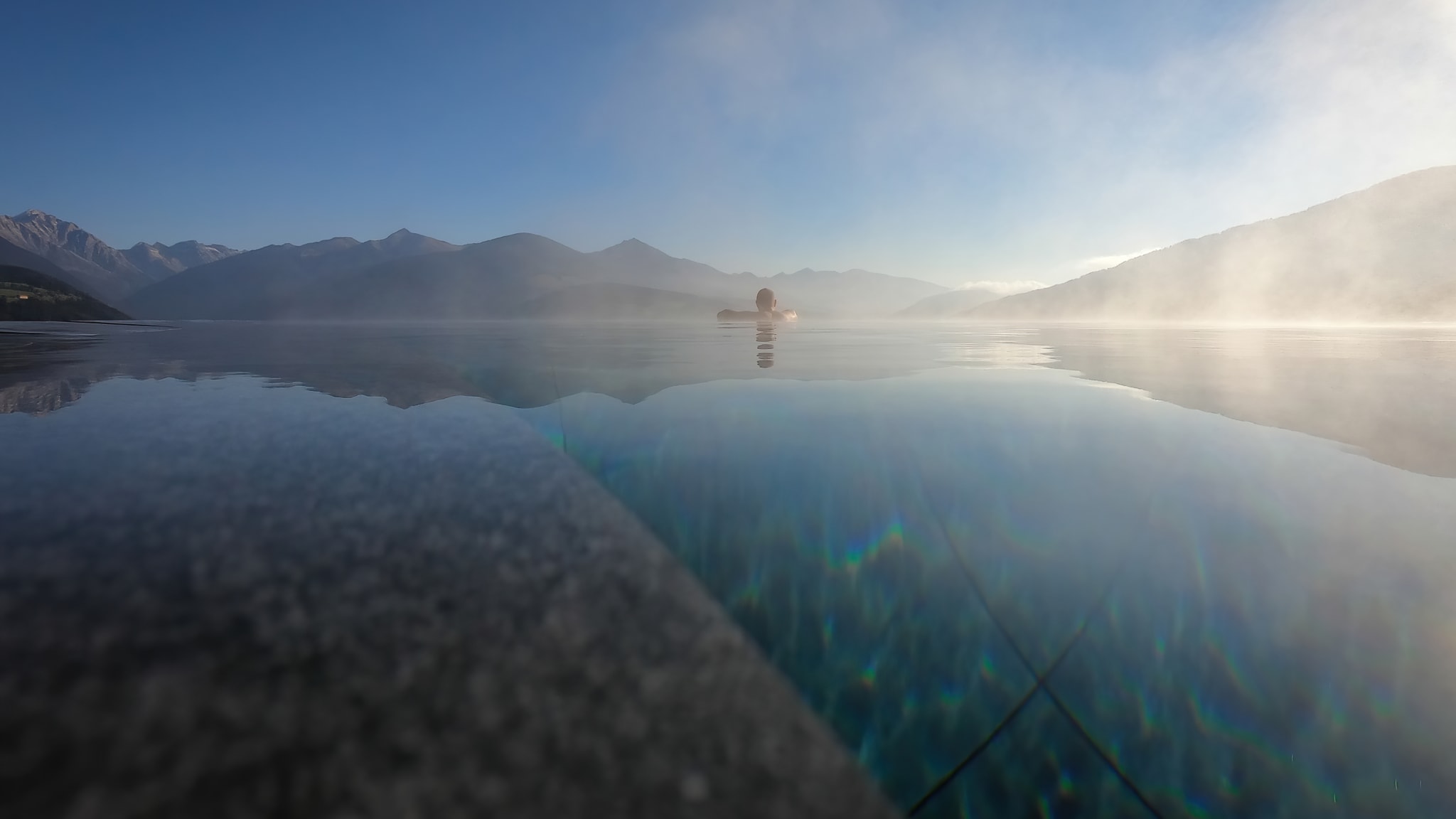 Ein Mann genießt in einem Infinity Pool den Ausblick.