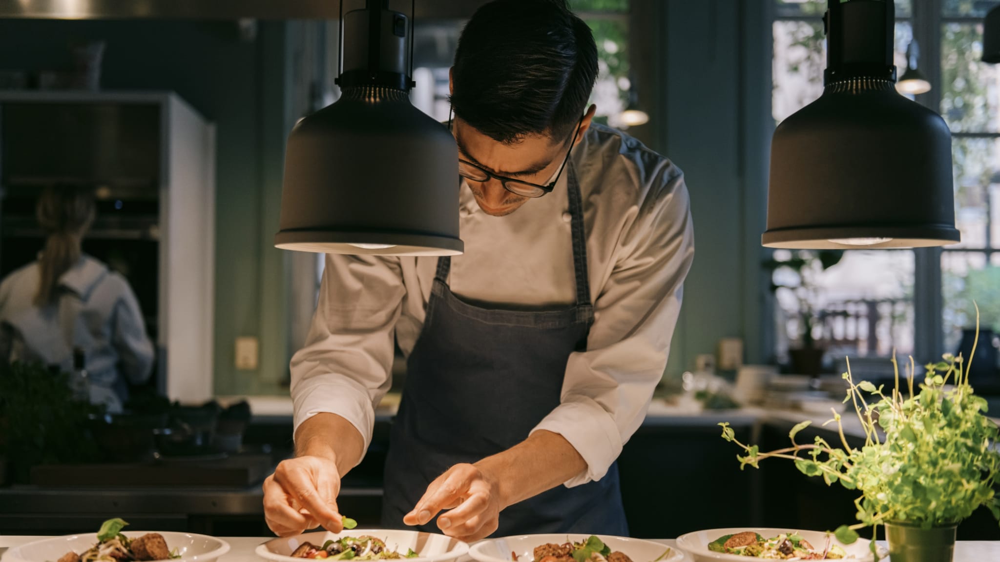 Ein Mann richtet Essen in einem Restaurant an. © Maskot/Maskot via Getty Images