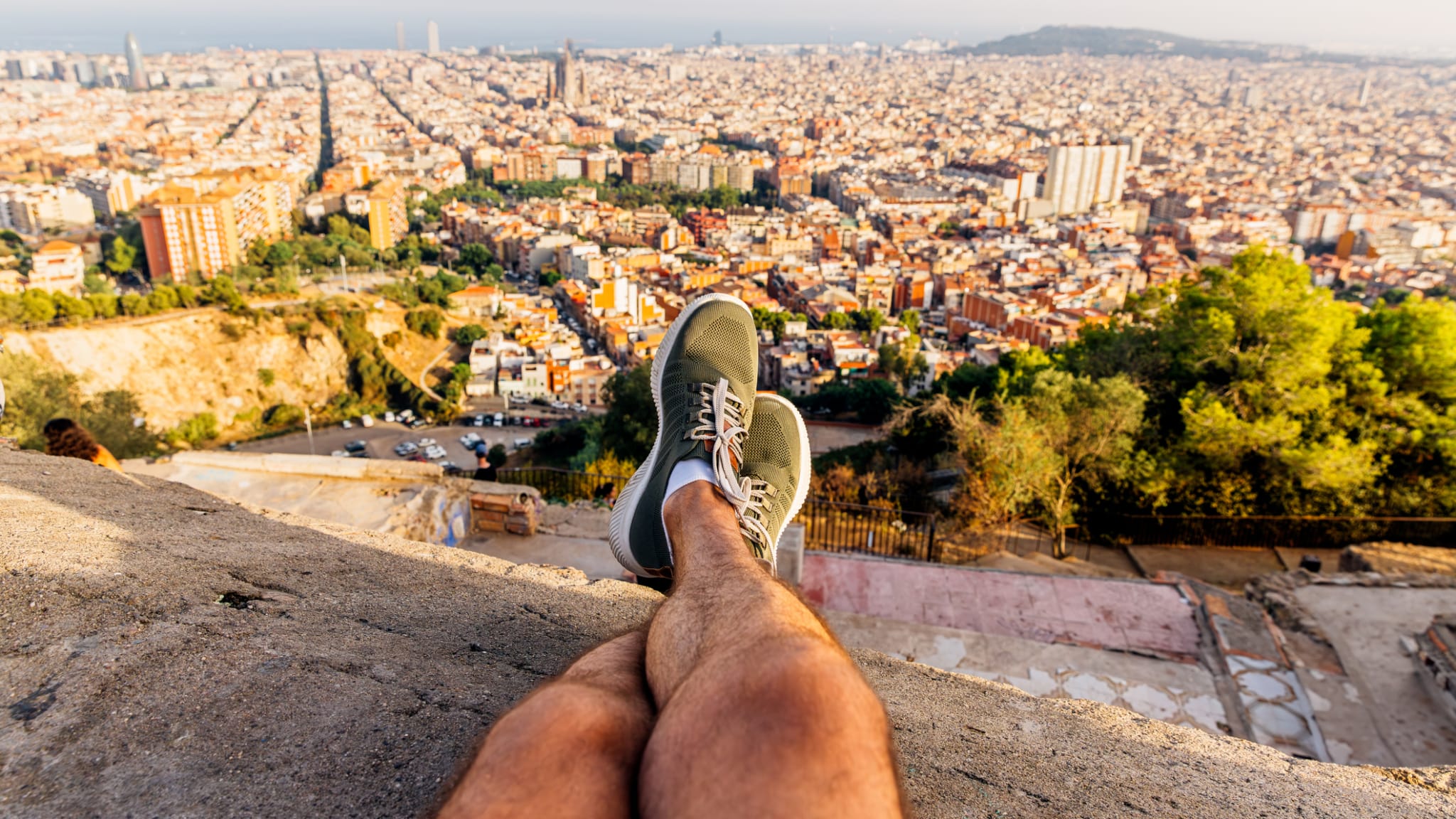 Ein Mann sitzt auf einer Mauer und schaut auf Barcelona.