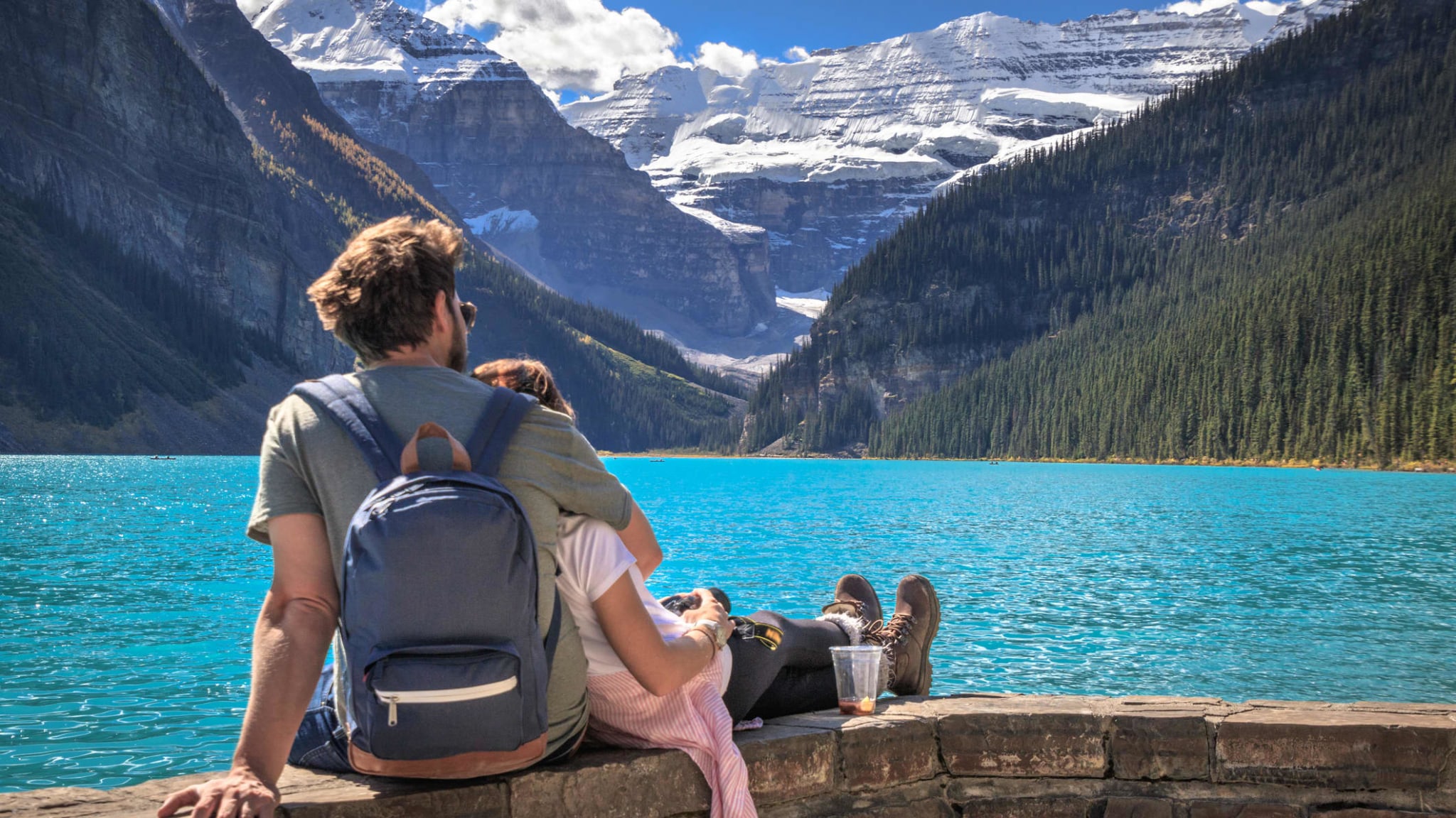 Ein Pärchen sitzt Arm in Arm am Lake Louise im Banff Nationalpark in Kanada.