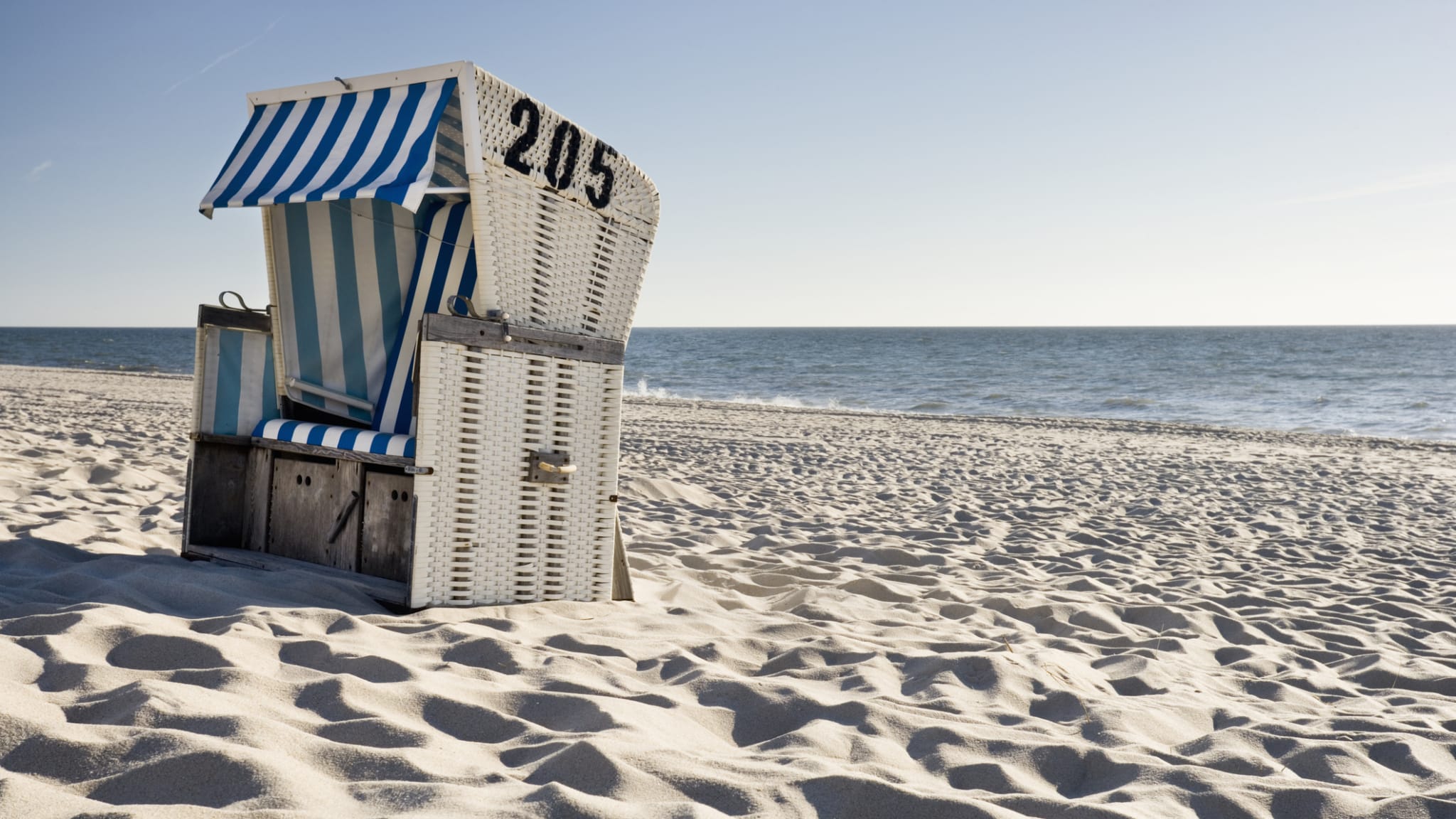 Ein Strandkorb steht an einem leeren Strand.