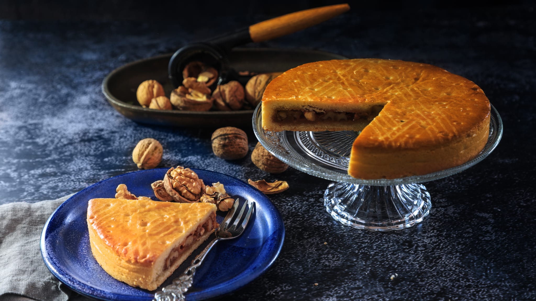 Ein Stück Bündner Nusstorte auf einem Teller neben der restlichen Torte. © yuelan/iStock / Getty Images Plus via Getty Images