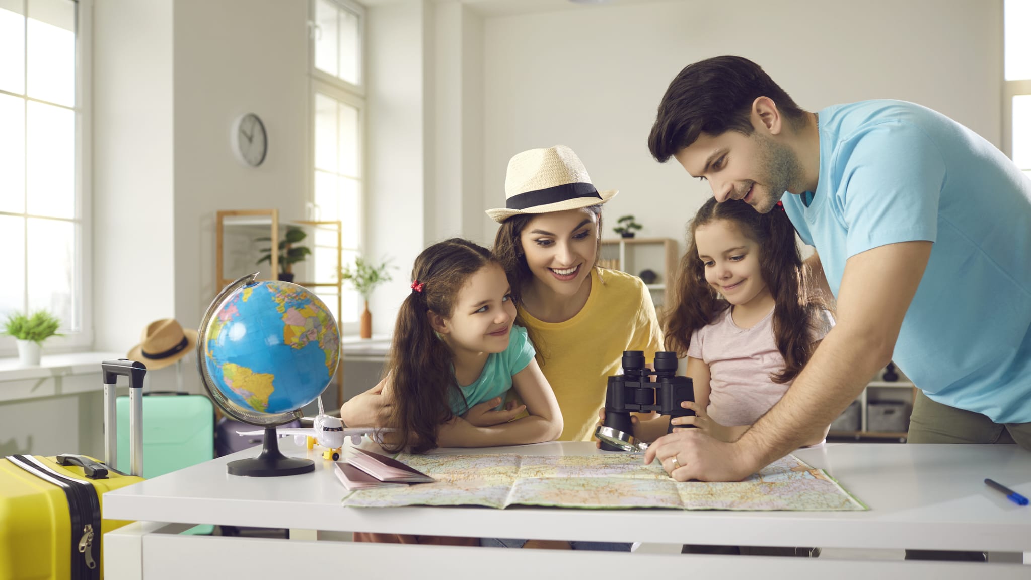 Eine Familie plant zuhause gemeinsam ihren Urlaub. © Lacheev/iStock / Getty Images Plus via Getty Images