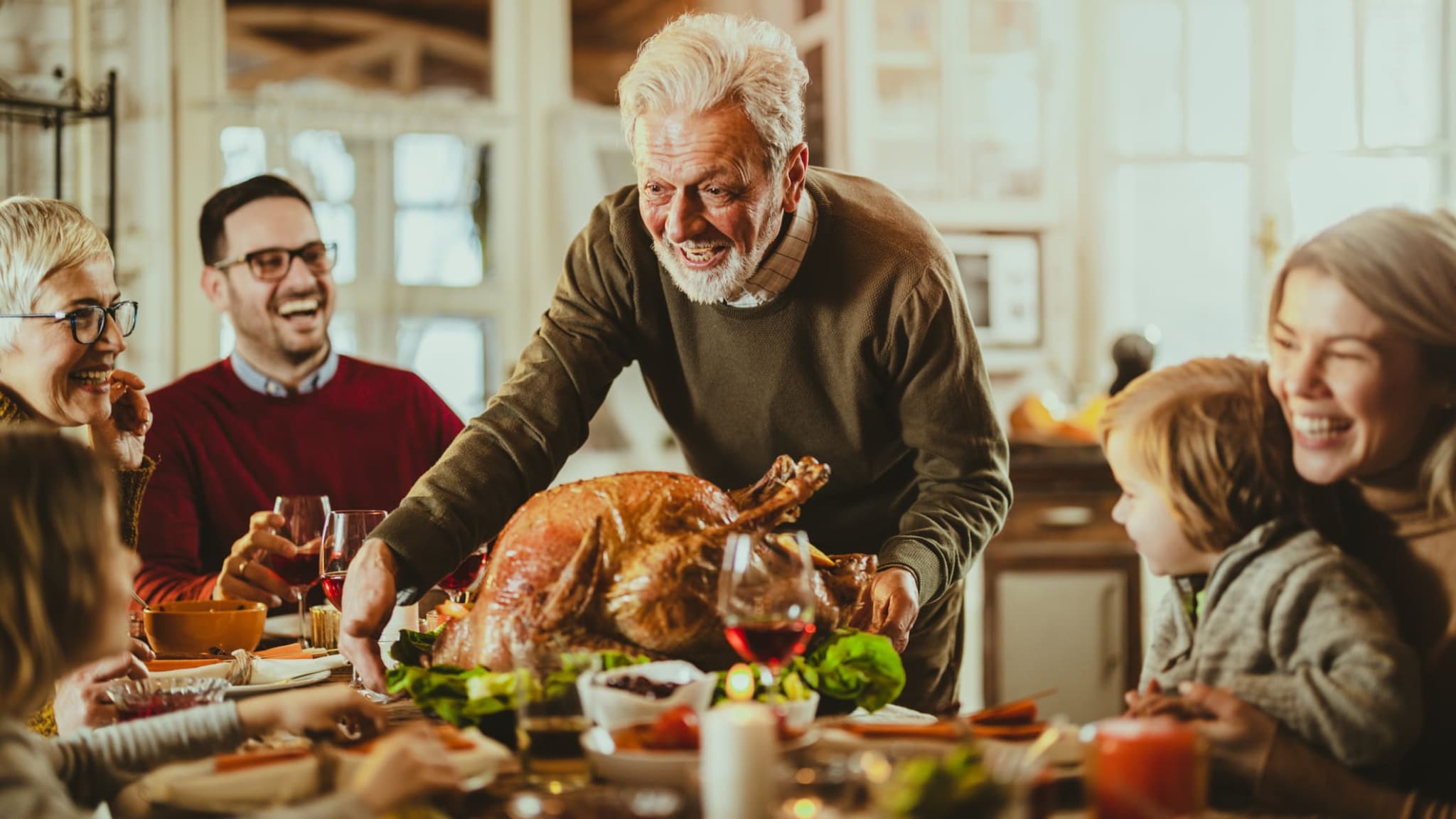 EIne Familie sitz an einem Tisch um Thanksgiving zu feiern.