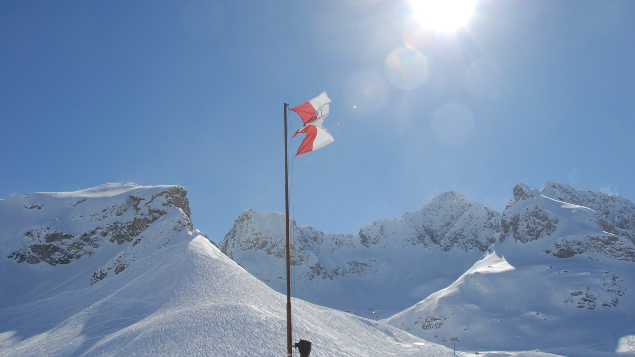 Eine Flagge weht zwischen verschneiten Bergen in Vorarlberg, Österreich.