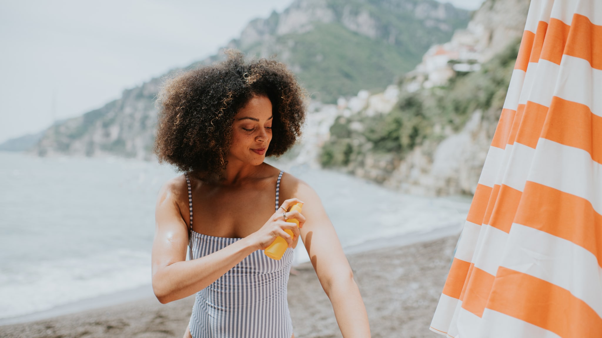 Eine Frau cremt sich am Strand mit Sonnencreme ein.