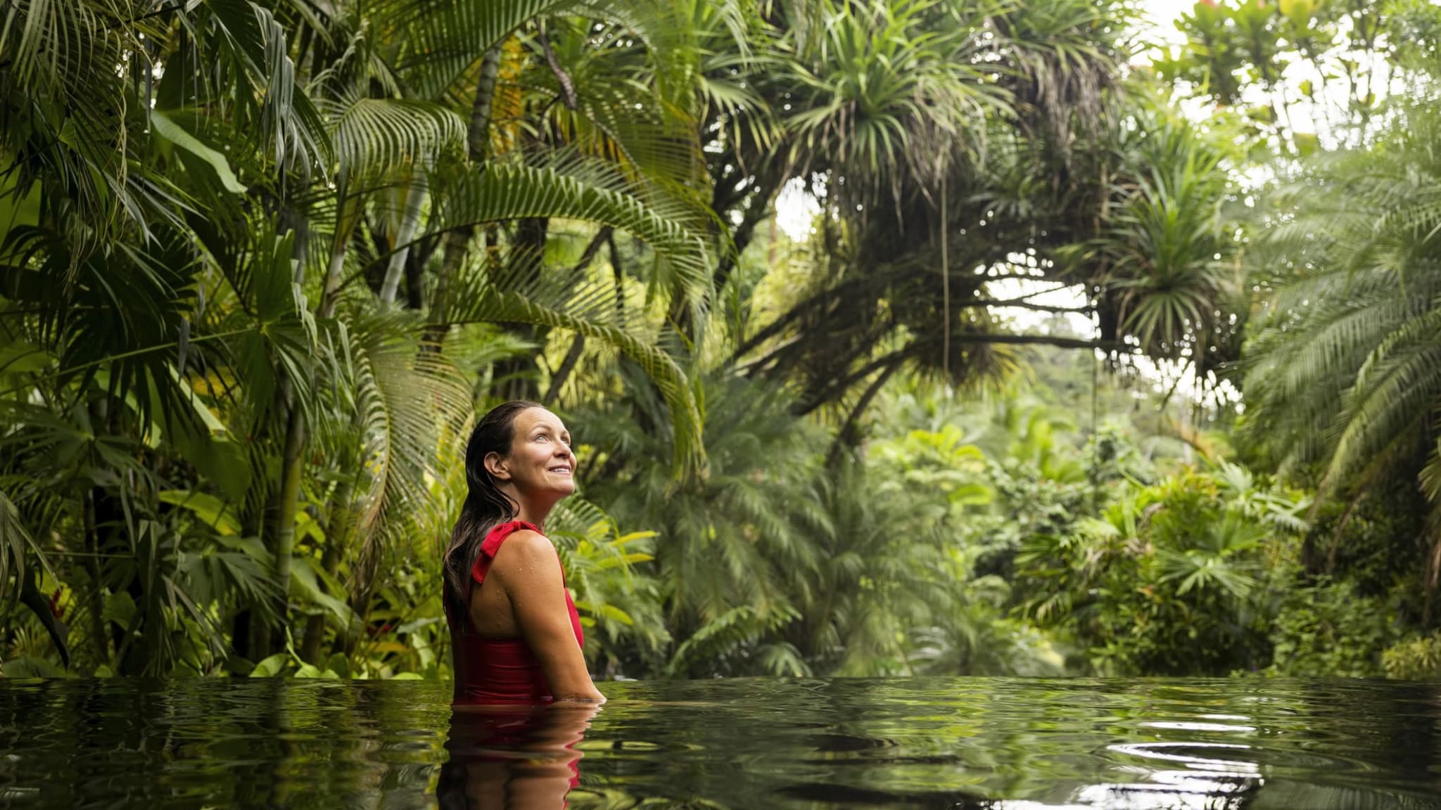 Eine Frau lächelt in einem Pool im Dschungel von Costa Rica.