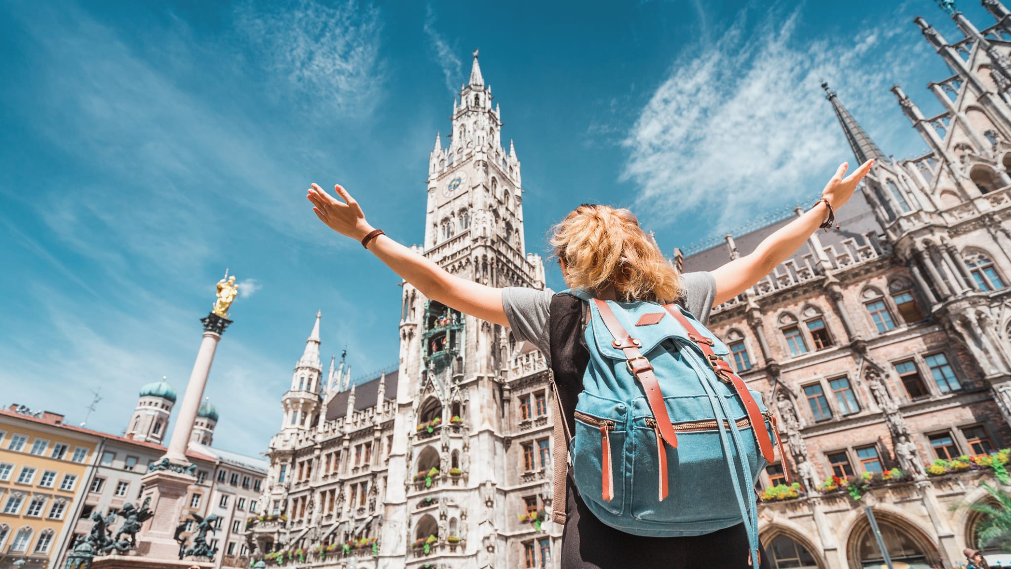 Eine Frau mit einem Rucksack steht vor dem Münchner Rathaus.