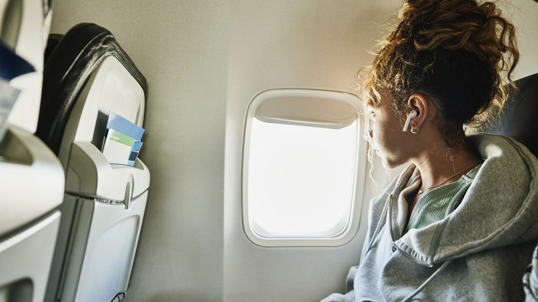 Eine Frau mit Kopfhörern sitzt in einem Flugzeug.