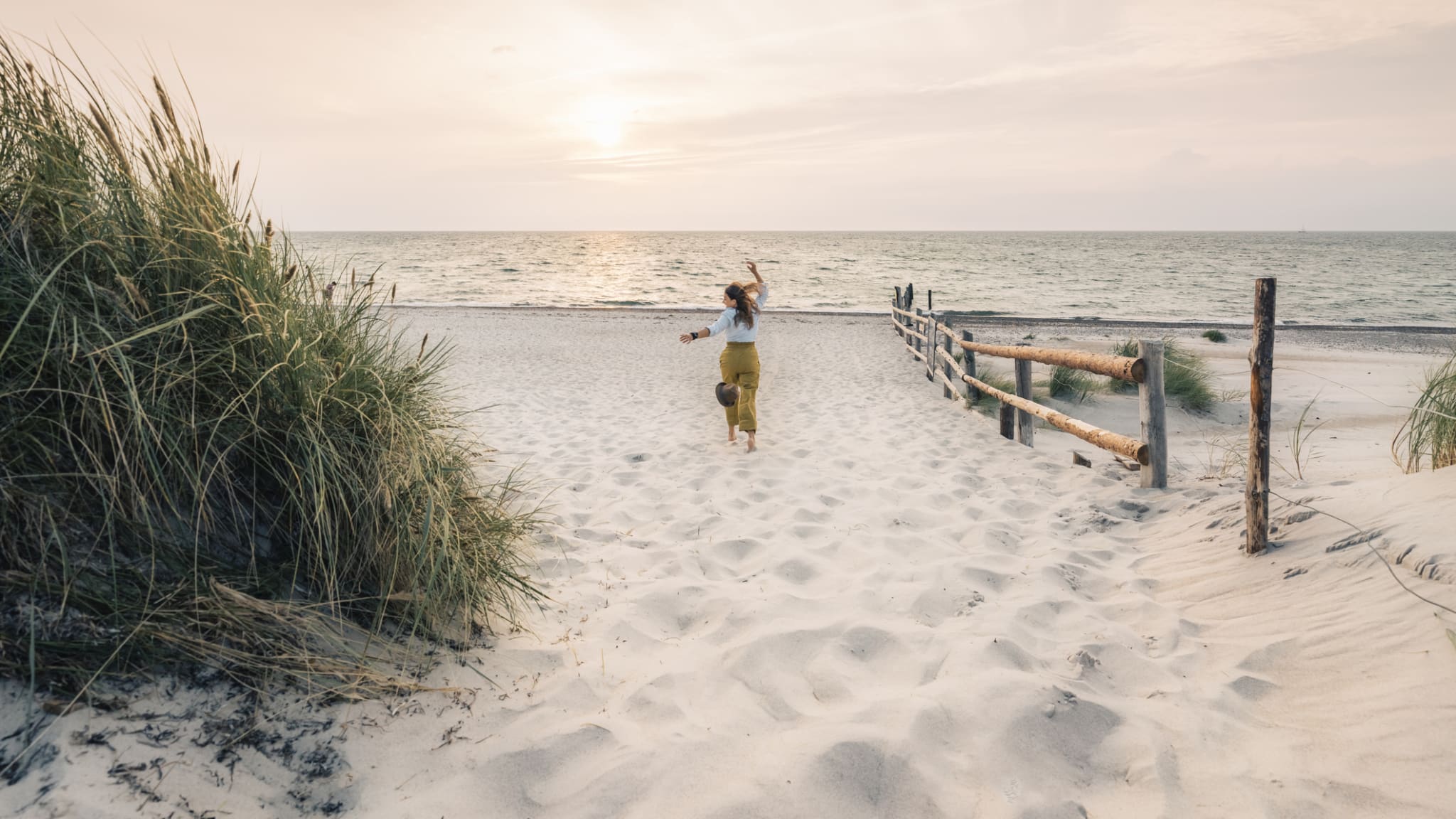 Eine Frau rennt einen Strand in Mecklenburg-Vorpommern, Deutschland, entlang. © Francesco Vaninetti Photo/Moment via Getty Images