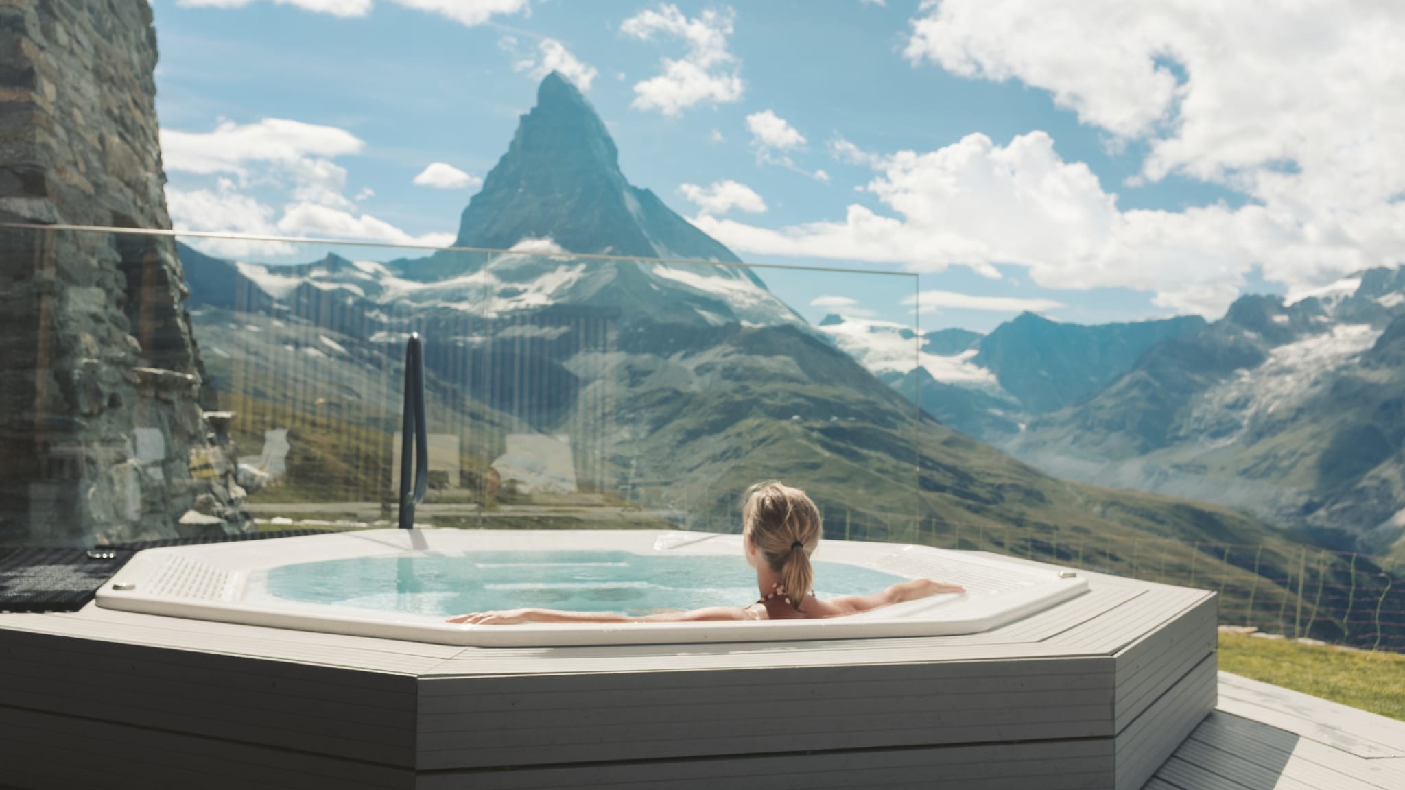 Eine Frau schaut von einem Whirlpool auf die Berge.