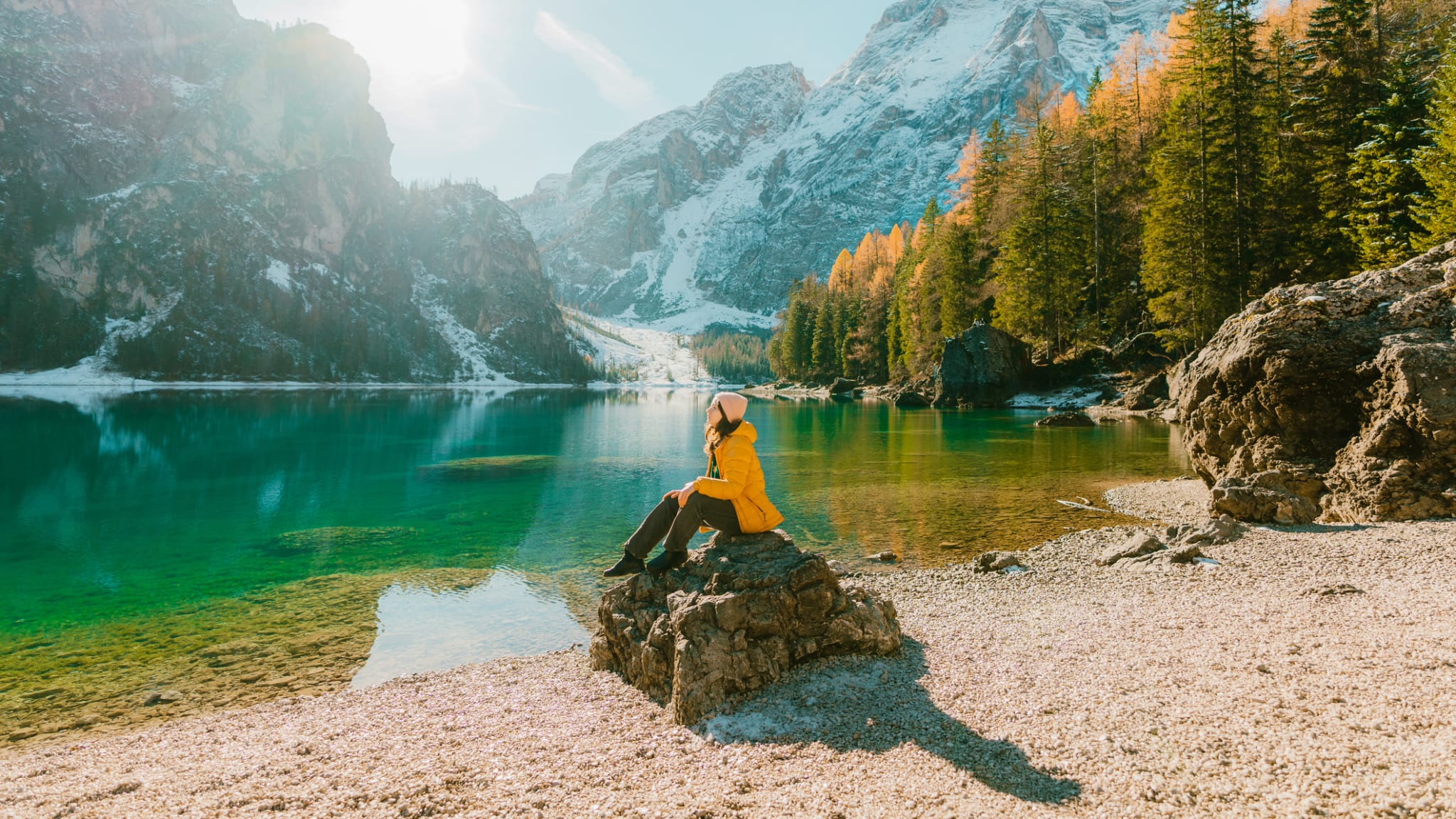 Eine Frau sitzt auf einem Stein am Lago di Braies.