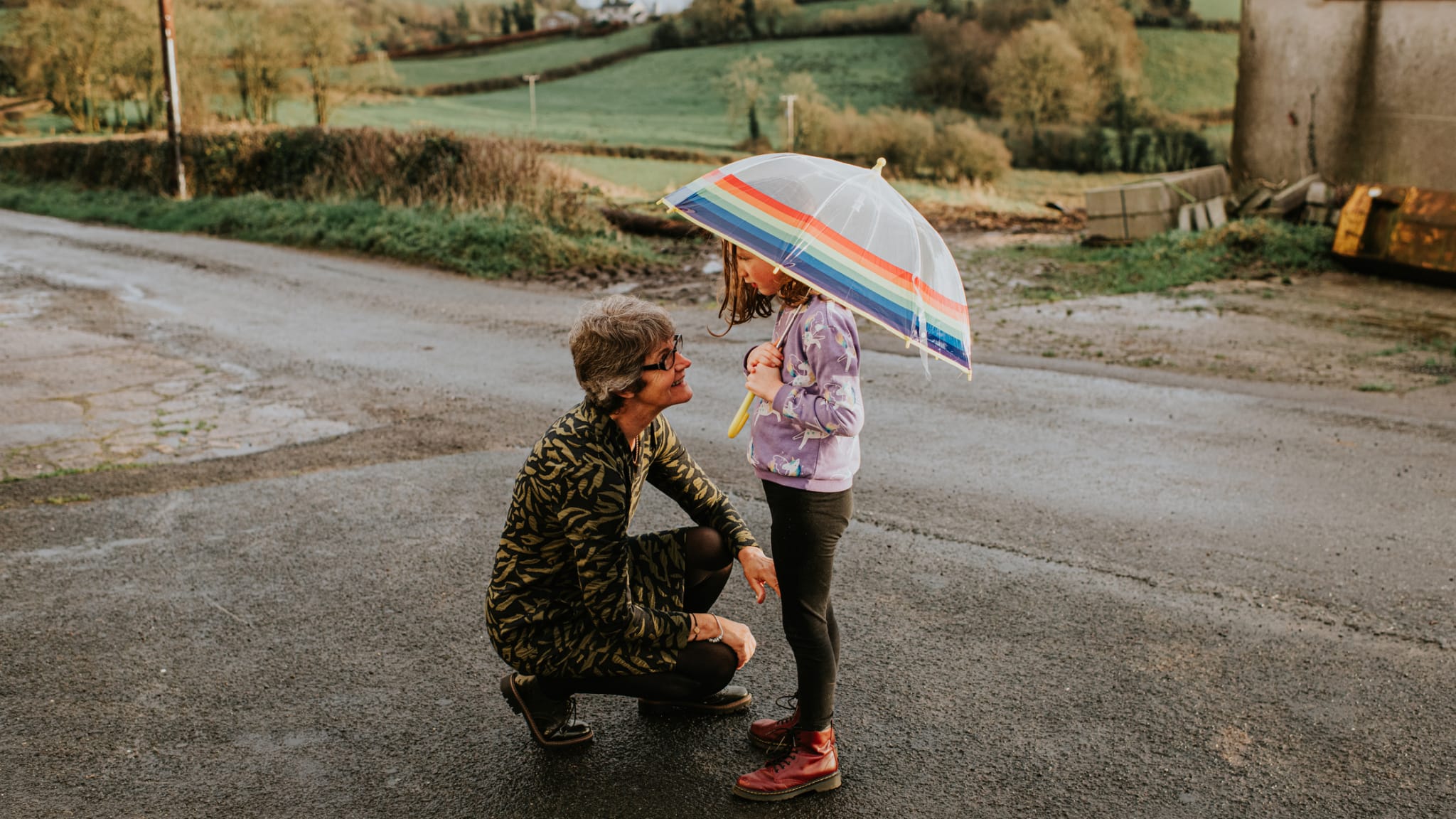 Eine Großmutter kniet vor ihrer Enkelin, die einen Regenschirm hält. © Catherine Falls Commercial/Moment via Getty Images