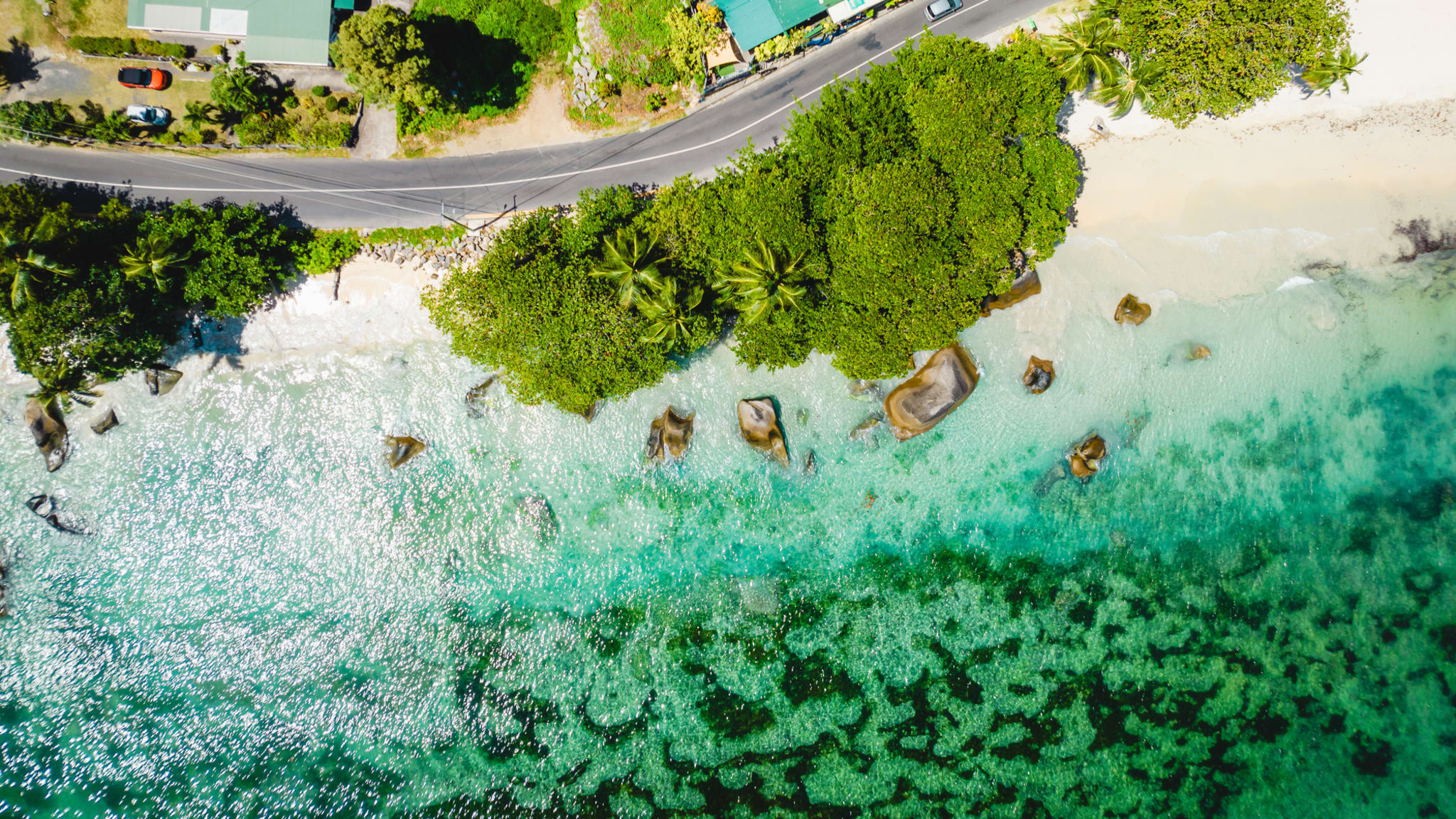 Eine Küstenstraße direkt am Strand entlang auf Mahé, Seychellen.