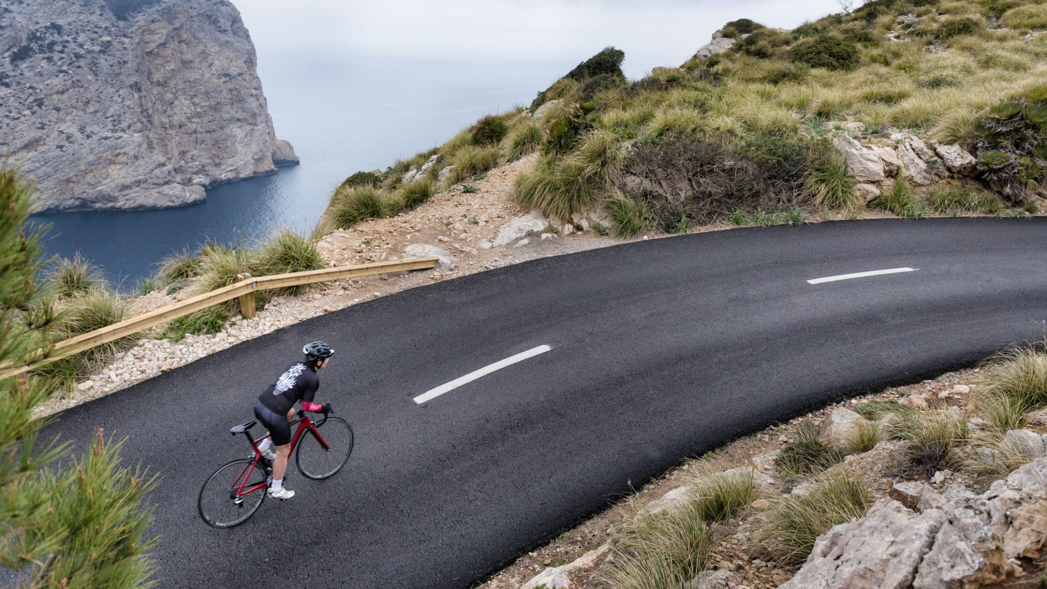 Eine Person fährt Fahrrad auf einer Küstenstraße, Mallorca, Balearen, Spanien.